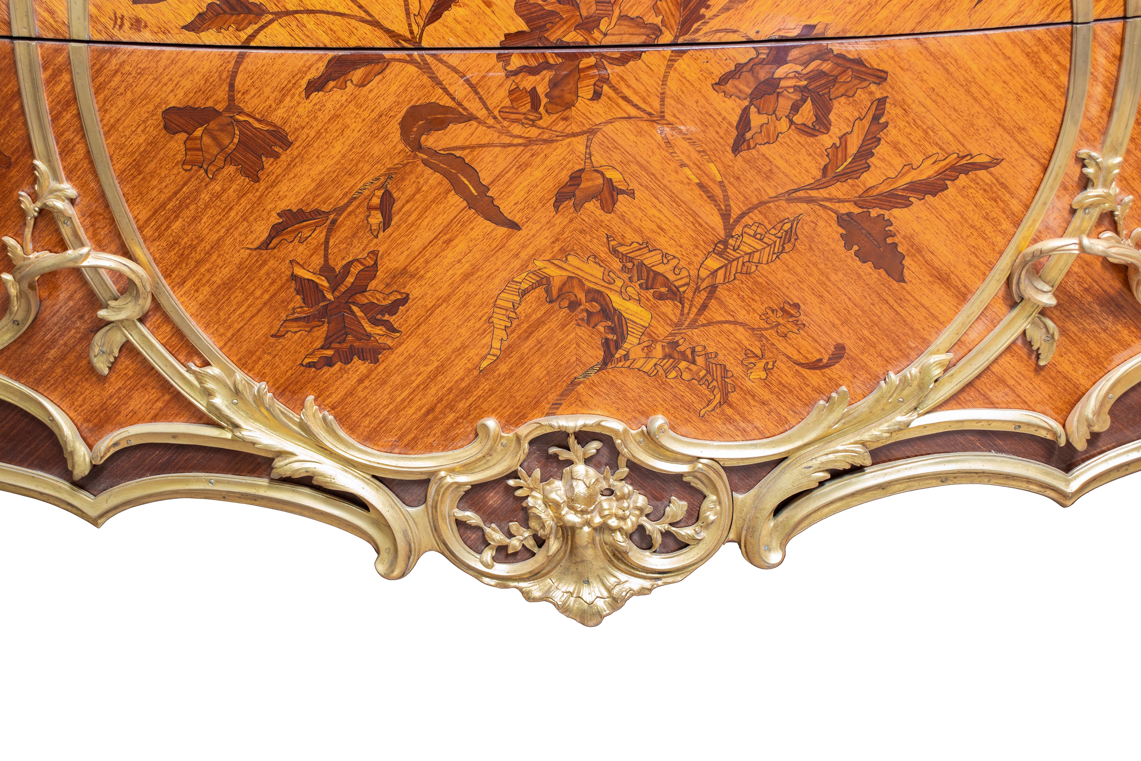 Pair of French 19th Century commodes in the Louis XV style. The curved solid wood bodies are adorned with glossy lacquered marquetry with foliage motifs. The ormolu mounts frame the entire structure, including the feet, featuring rocaille motifs and