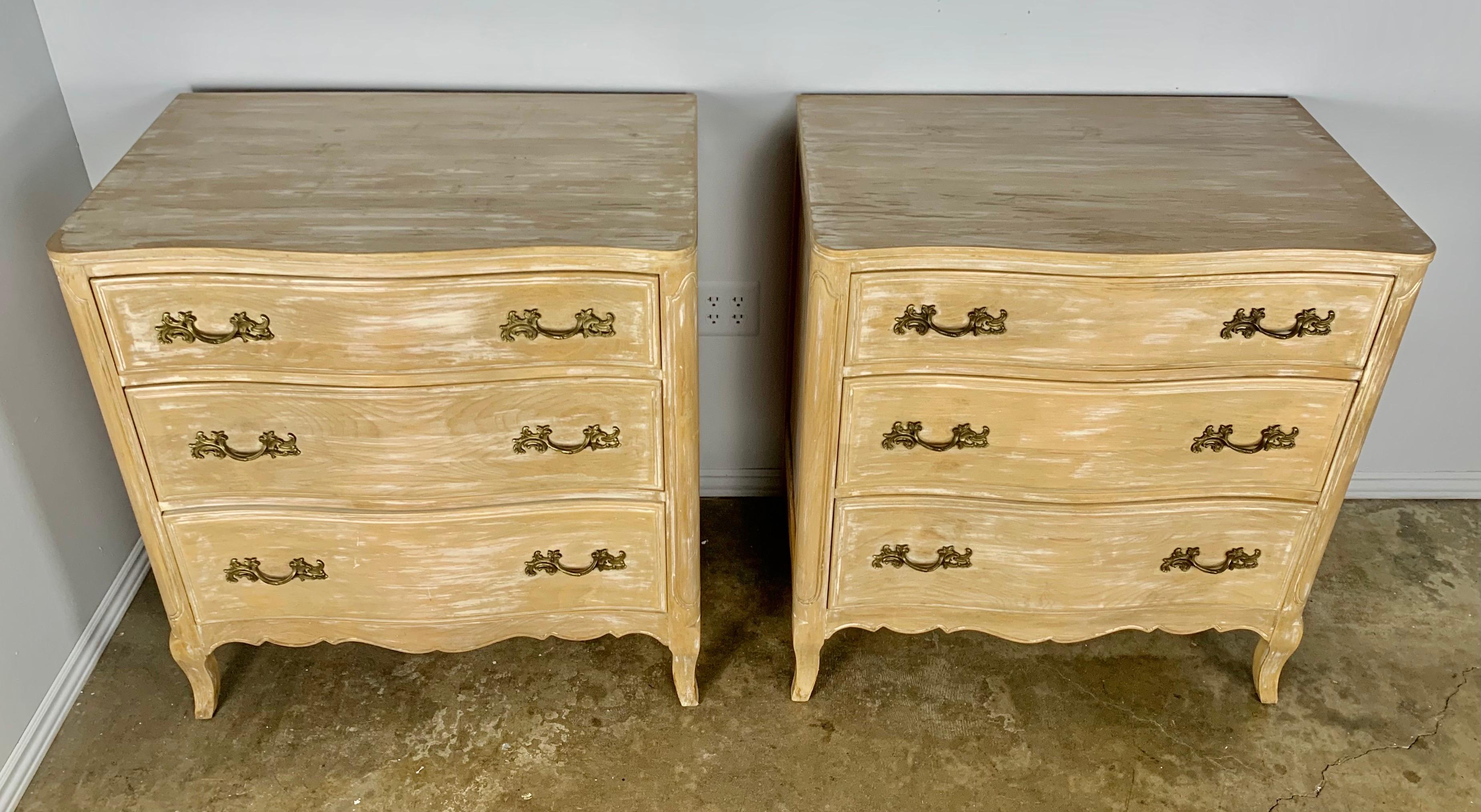 Pair of 3-drawer Louis XV French commodes with cast bronze hardware. The chests stand on four cabriole legs and have a scalloped apron at the bottom. There are remnants of paint left from another time period but they are nicely waxed and have