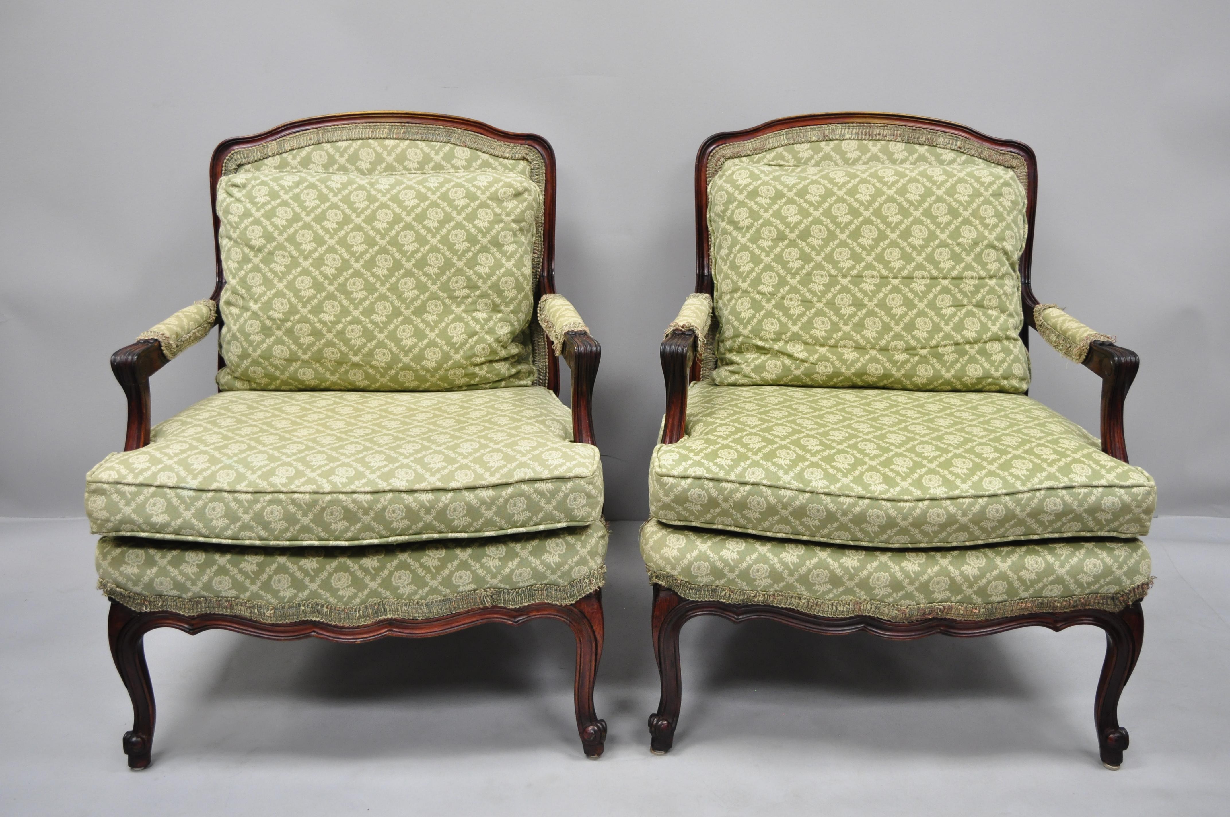 Pair of French Country Louis XV style mahogany Bergere armchairs. Item features nice wide seats, green fabric with floral pattern, solid wood construction, upholstered armrests, distressed finish, cabriole legs, great style and form, circa mid-20th