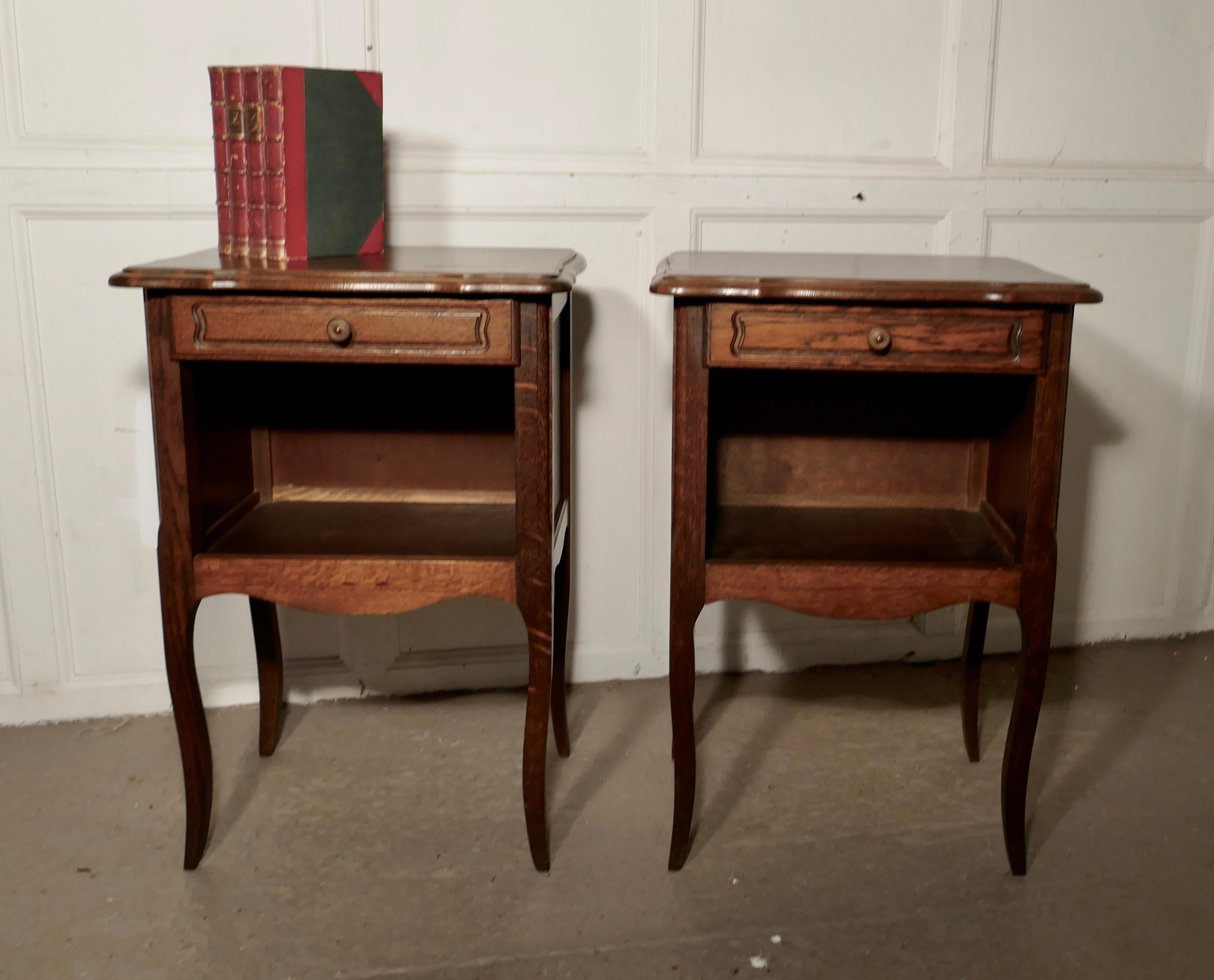Pair of French country oak bedside cabinets 

This is a pretty pair of cabinets or chevets, they are made in oak and have a shaped top.
The cabinets have an open book shelf and a drawer, they stand on splayed legs,
The cabinets are in good