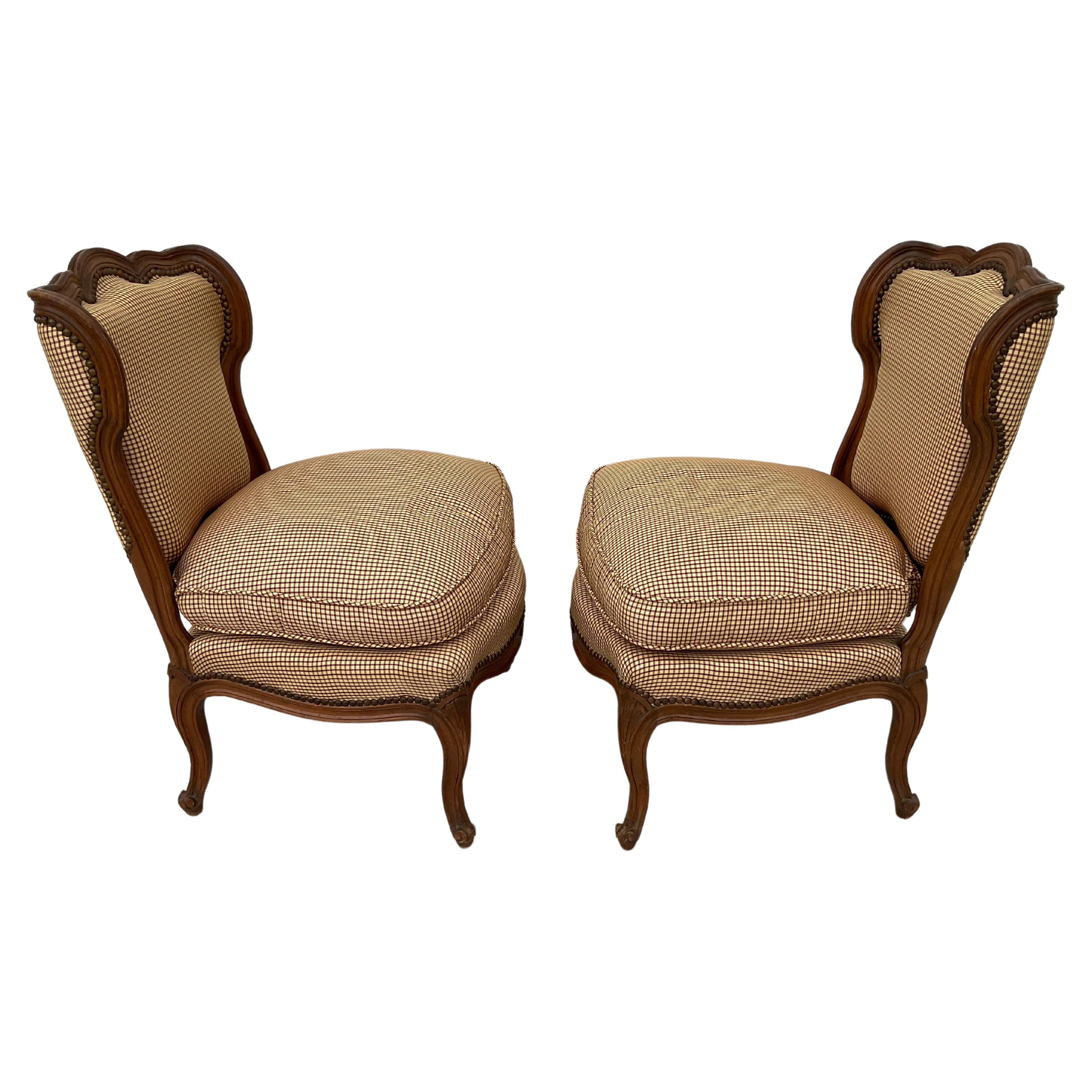 Pair of French country slipper chairs with wide comfortable seats. Upholstered chairs have beautifully shaped backs and are raised on scrolled cabriole legs. Upholstery is in a small brown and cream check. Versatile chairs can be used in any room or
