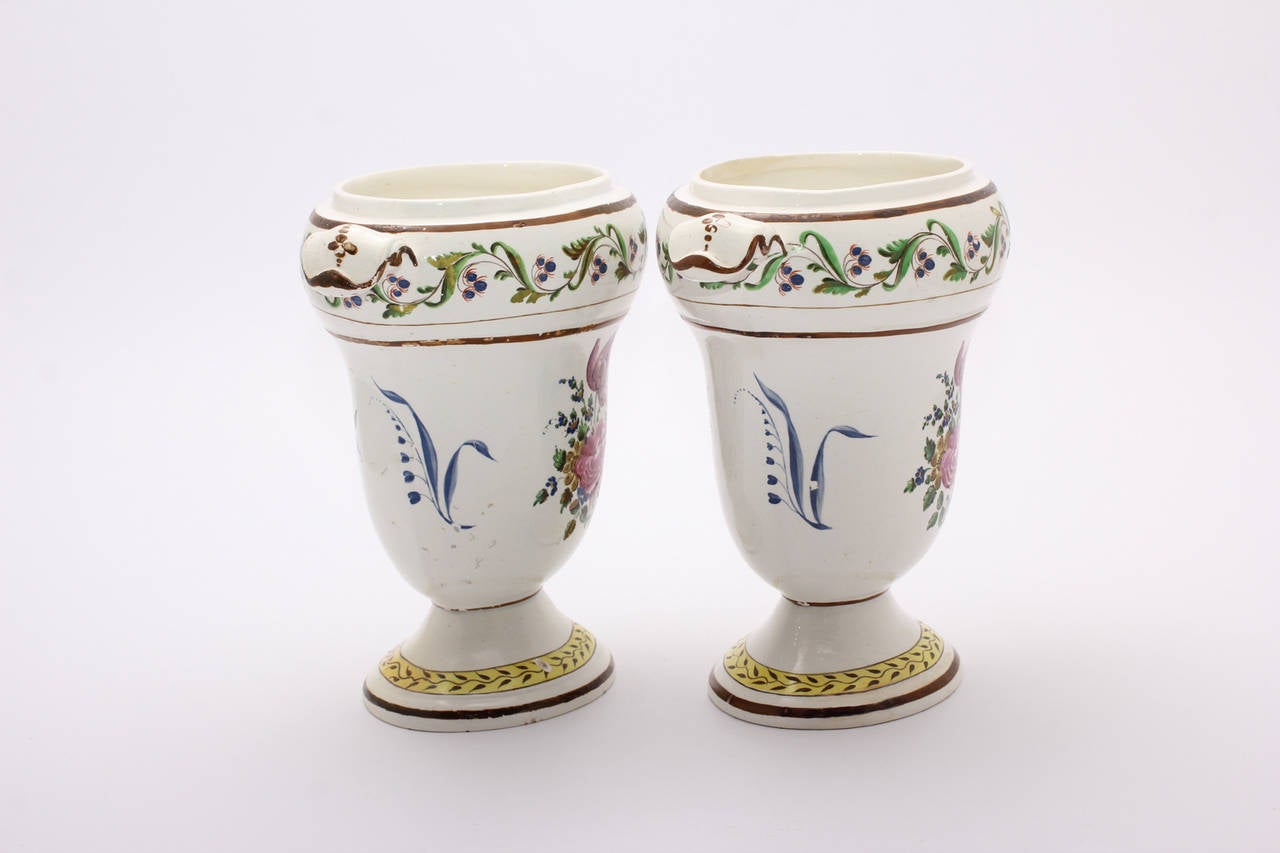 Pair of creamware pottery vases, of oval form with short spreading foot, painted with flower sprigs, the lower border with brown vine on yellow ground, the upper with scrolling cornflower, within brown line borders. 
Impressed mark TH. & O.