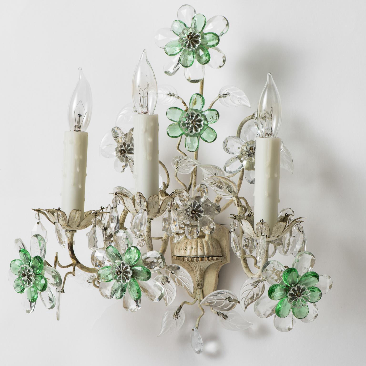 These charming three-light sconces featuring a white painted metal center urn and three arms ending in crystal flowers. The crystals are an unusual combination of clear and pale green giving them a light and airy feel. They have been recently