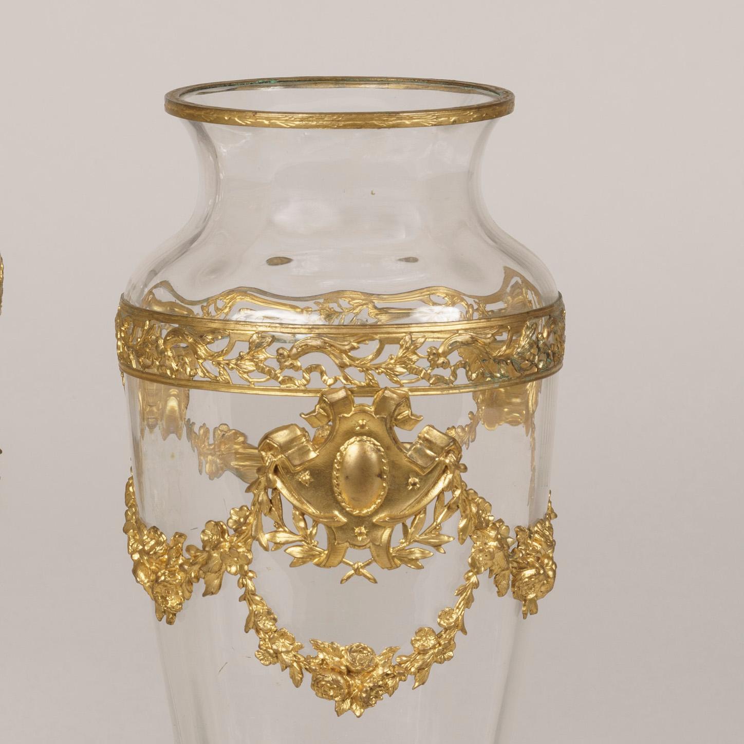 A pair of crystal glass vases attributed to Baccarat

Of inverted baluster ribbed form, and dressed with gilt bronze pierced bands, and foliate swags and garlands in the Belle Époque taste.
French, circa 1900

Baccarat
A licence and permission