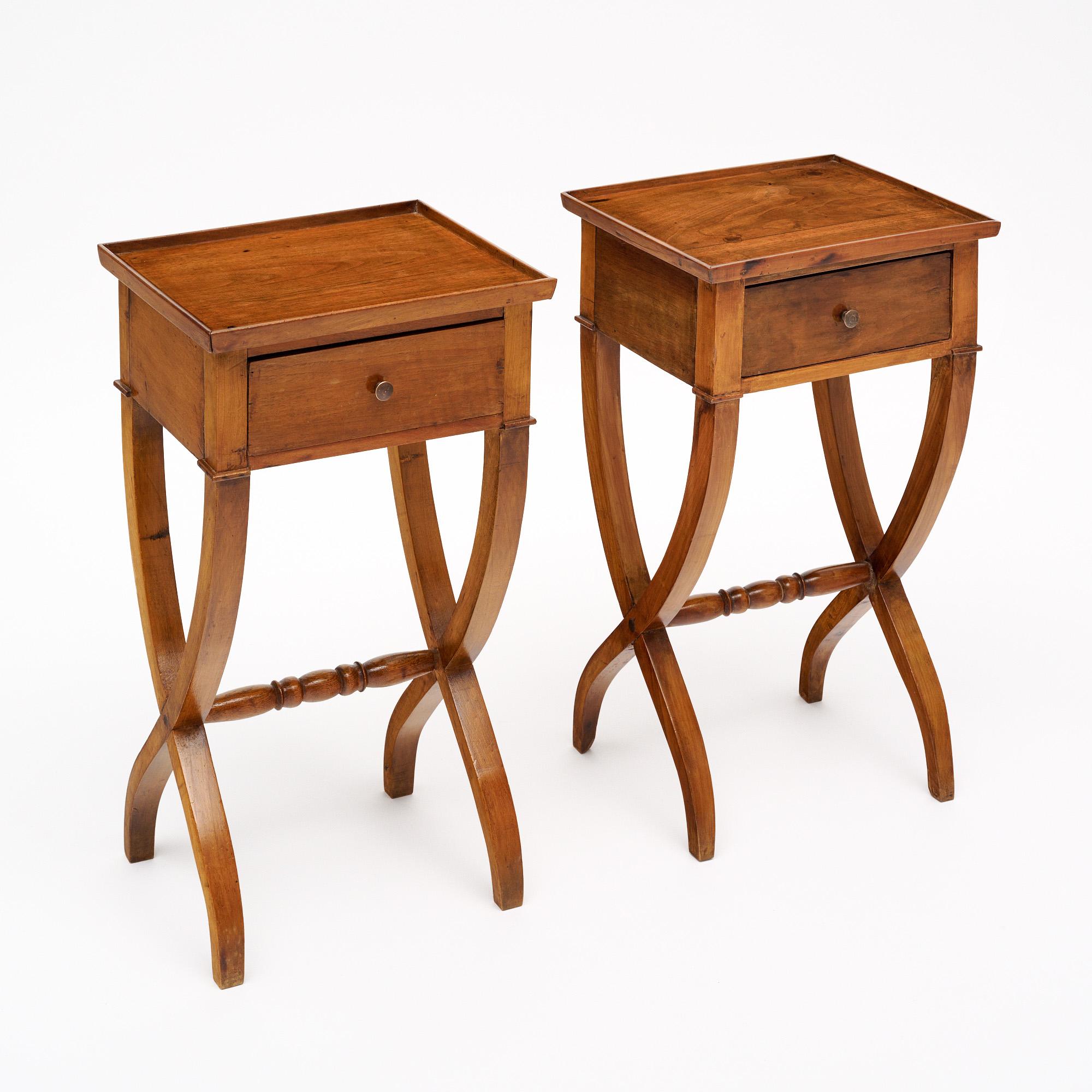 Paire de tables d'appoint françaises en bois massif, principalement en cerisier. Chaque table est finie avec un vernis français lustré de qualité muséale. Les tables présentent un magnifique design de pieds en curule et un châssis sculpté à la main.
