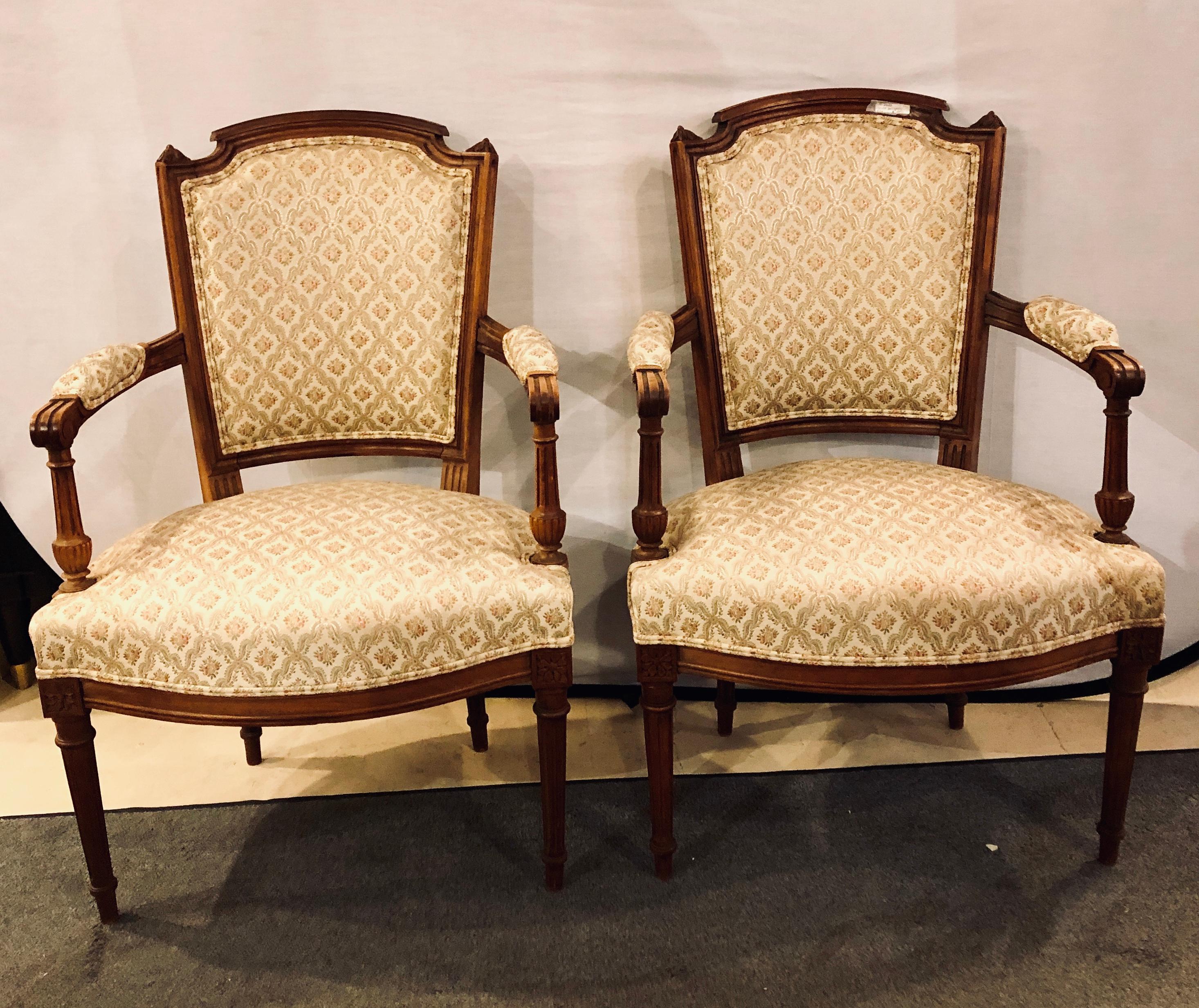 A fine pair of French custom Louis XVI style carved bergere or armchairs each in a nice fabric with carved lines and open side arms.