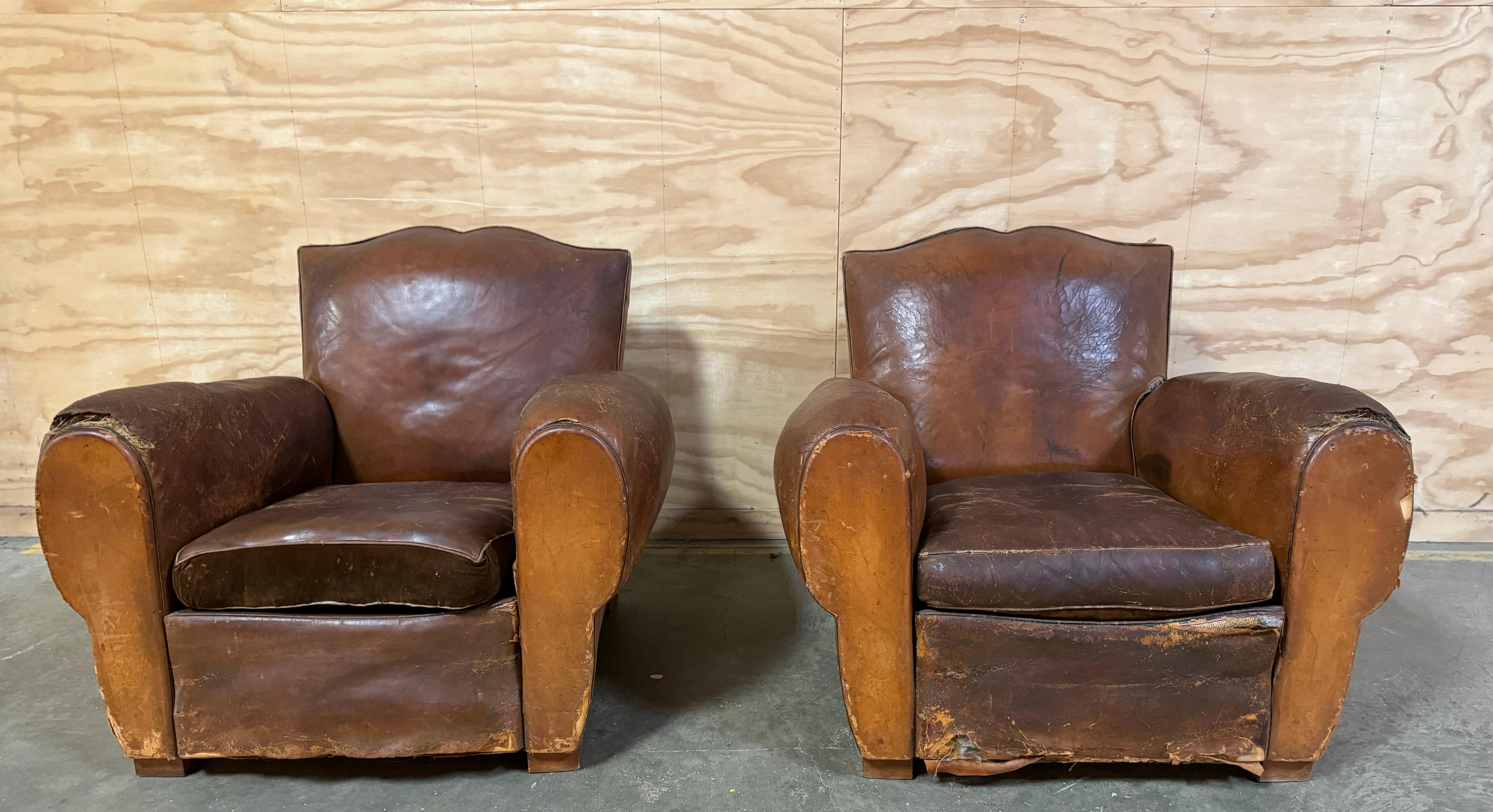A pair of Large Vintage Art Deco Distressed Leather French Club Chairs.

All original.

Details:
Very fine patina to the leather.

Seat cushions reverse from leather on one side to brown velvet on the other side.

Brass stud trim to back.

Wood