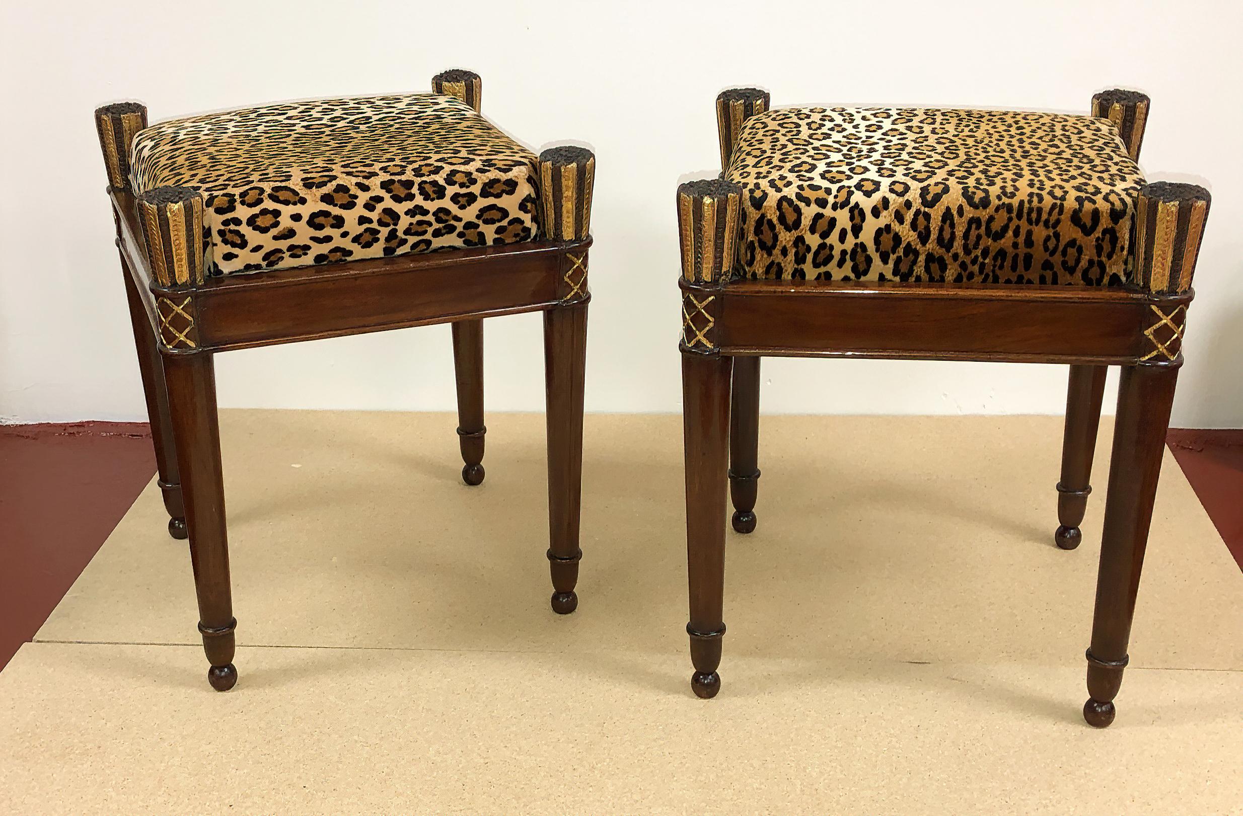 A fine pair of French Directoire mahogany stools with crushed velvet Leopard upholstery, a square mahogany frame with carved and gilded arrow feather and quiver form legs that are turned and tapered, and ending in ball feet.