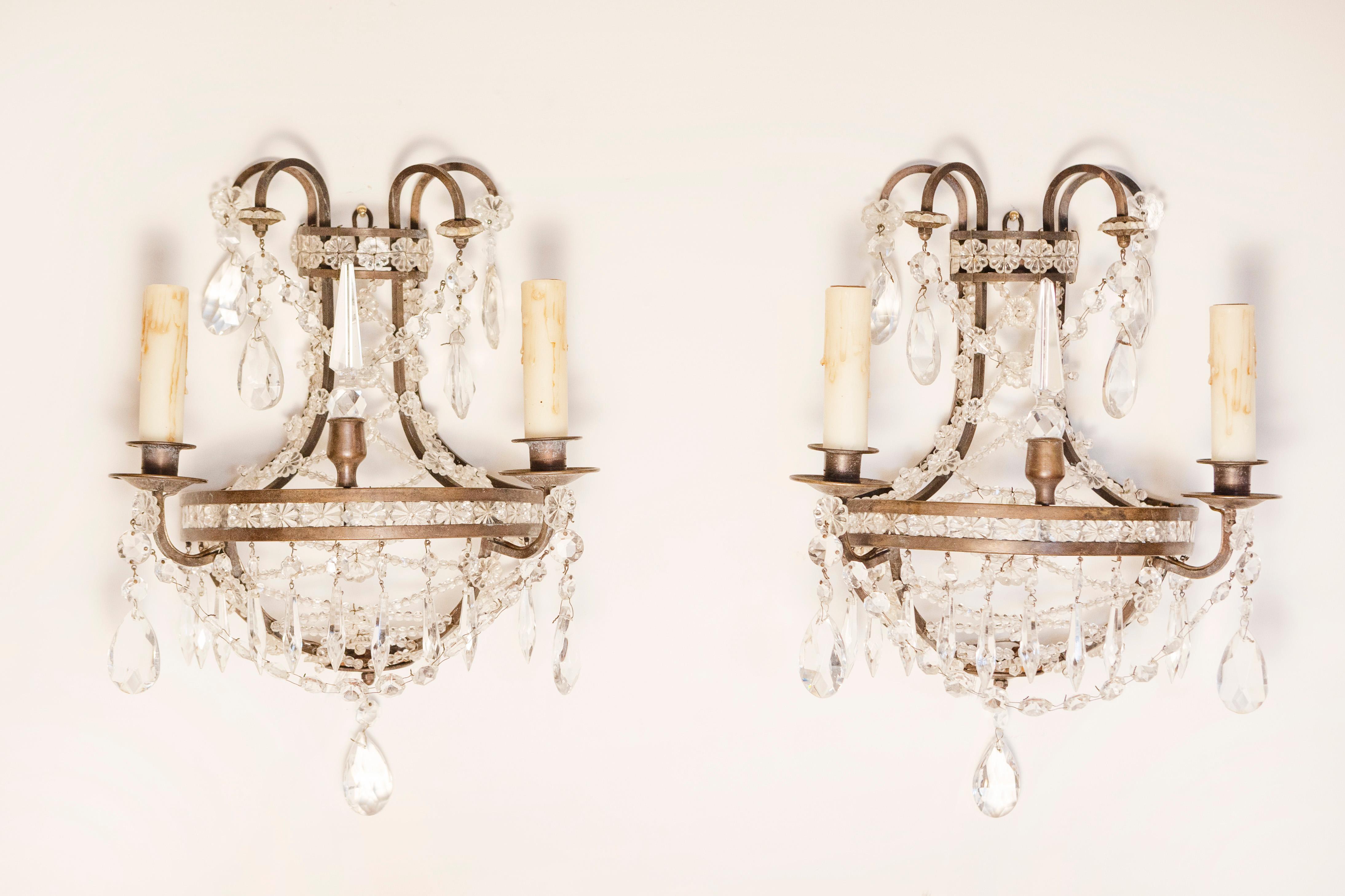 Paire d'appliques murales à deux lumières de style Directoire français du 20e siècle, avec armature en bronze, rosettes en cristal et motifs d'obélisques. Cette exquise paire d'appliques murales à deux lumières de style Directoire français du XXe