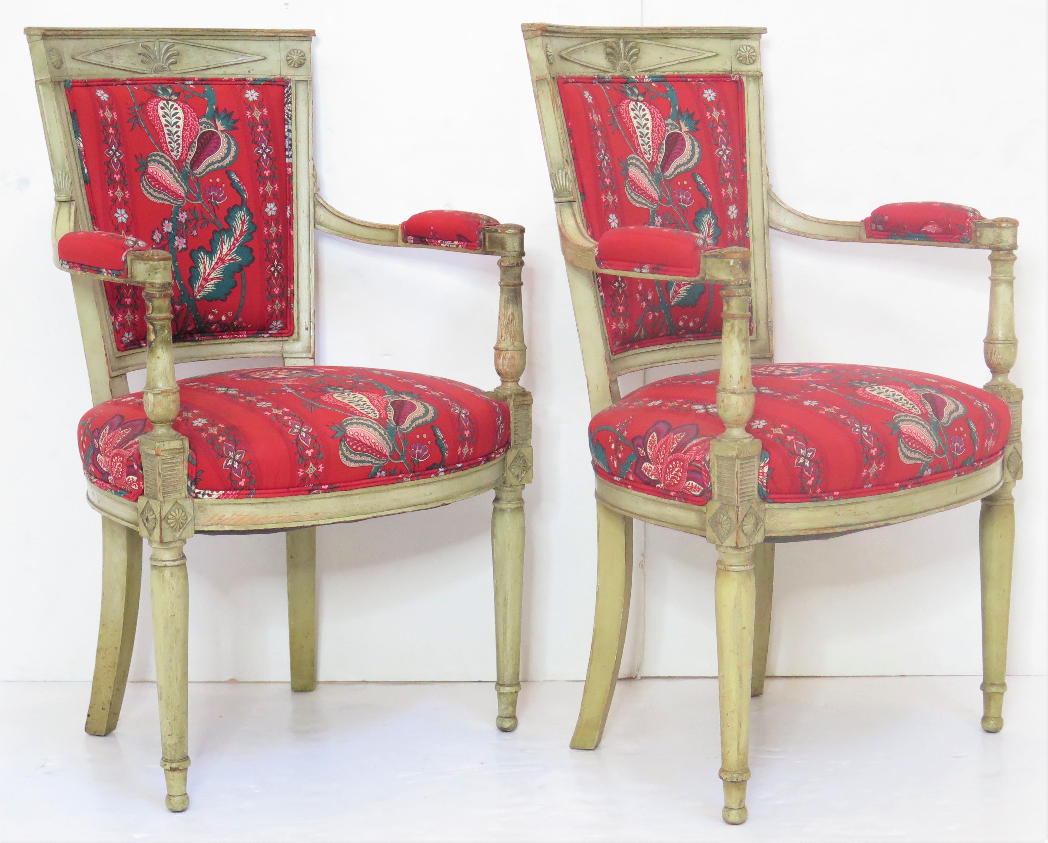 a pair of handsome French Directoire-style fauteuils with painted frames in off white or cream, carved anthemion and rosettes decoration, turned tapered front legs, upholstered seat, back, and arm rests, great vintage fabric in bright red 