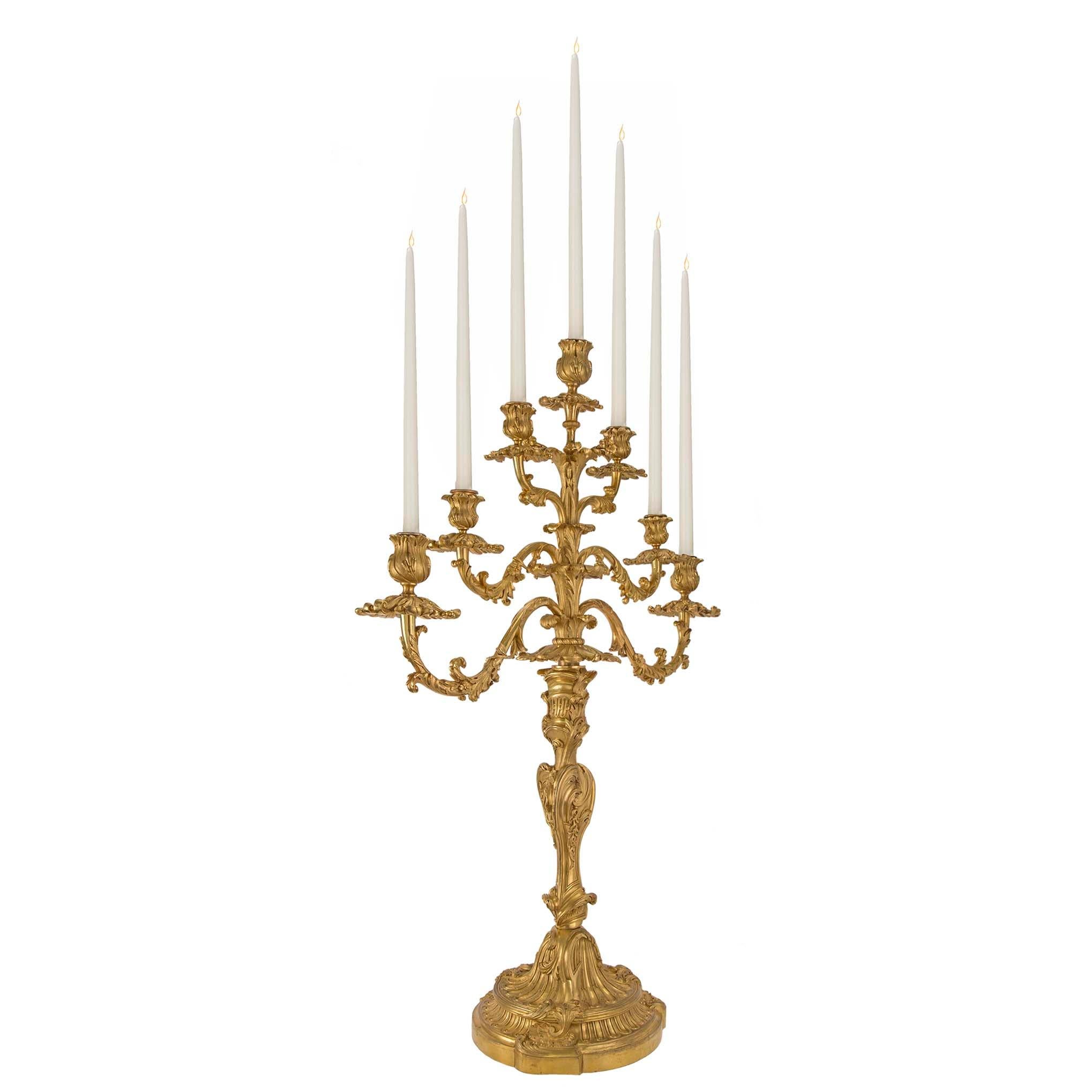 A stunning and monumental pair of French early 18th century Régence Period seven arm ormolu candelabras. Each statement making candelabra is raised by a striking mottled circular base with fabulous fluted and scrolled foliate patterns. The elegant