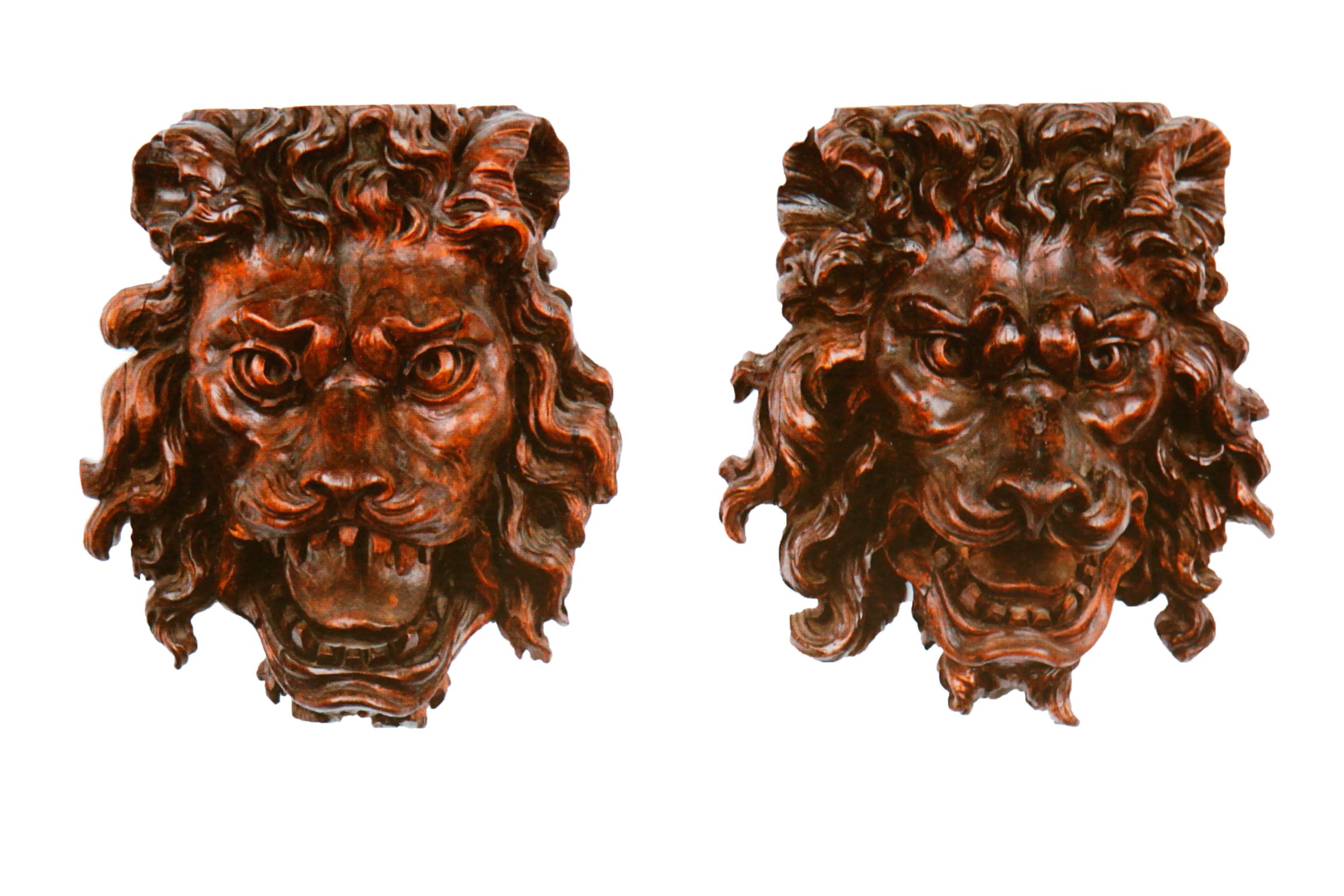 A pair of French early 19th century carved stained wood lion masks. Each on a later black metal rectangular stand.