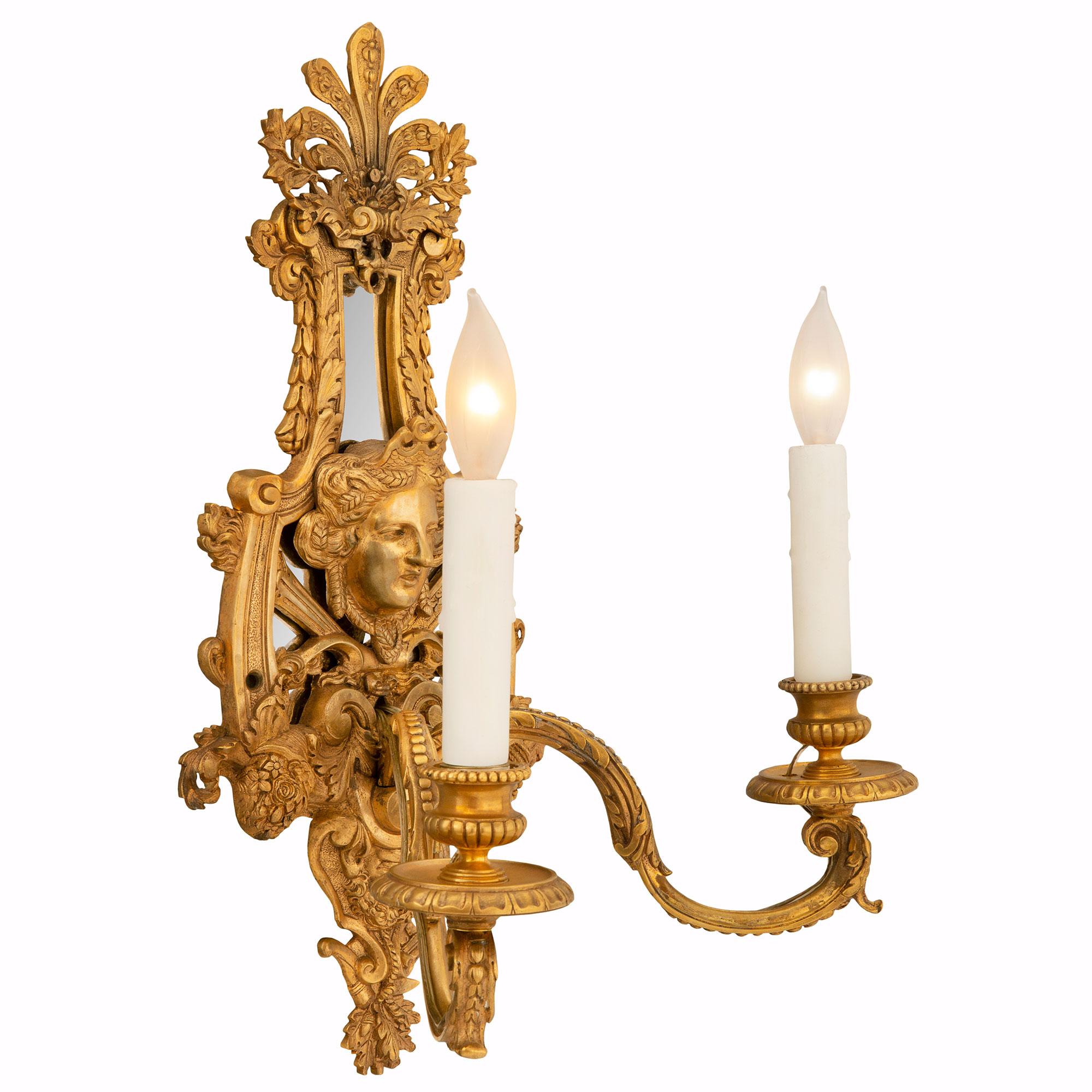 An exquisite pair of French early 19th century Louis XIV st. ormolu sconces. Each two arm sconce is centered by a striking and richly chased bottom foliate reserve with beautiful oak leaves and acorns with a pan flute and handsome bearded satyr. At
