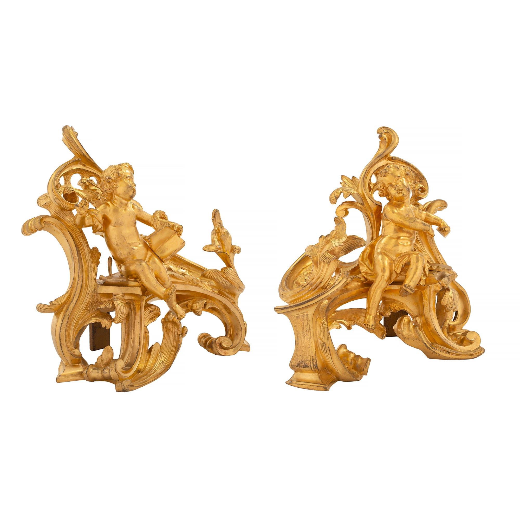 Paire de chenets en bronze doré de haute qualité, de style Louis XV, datant du début du XIXe siècle. Chaque chenet est surélevé par de magnifiques et très décoratifs mouvements de volutes aux captivants motifs feuillagés. De charmants chérubins sont