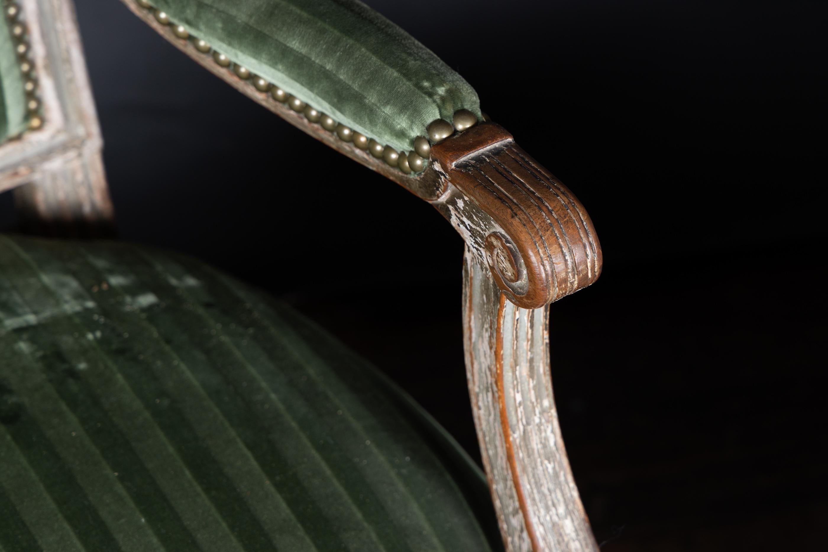 Paire de fauteuils de style Louis XVI du début du 19e siècle, sculptés et peints, avec un carré de marguerite au sommet de chaque pied cannelé, garnis de soie de velours coupée, attachés avec des agrafes de tapisserie. Les dossiers sont recouverts