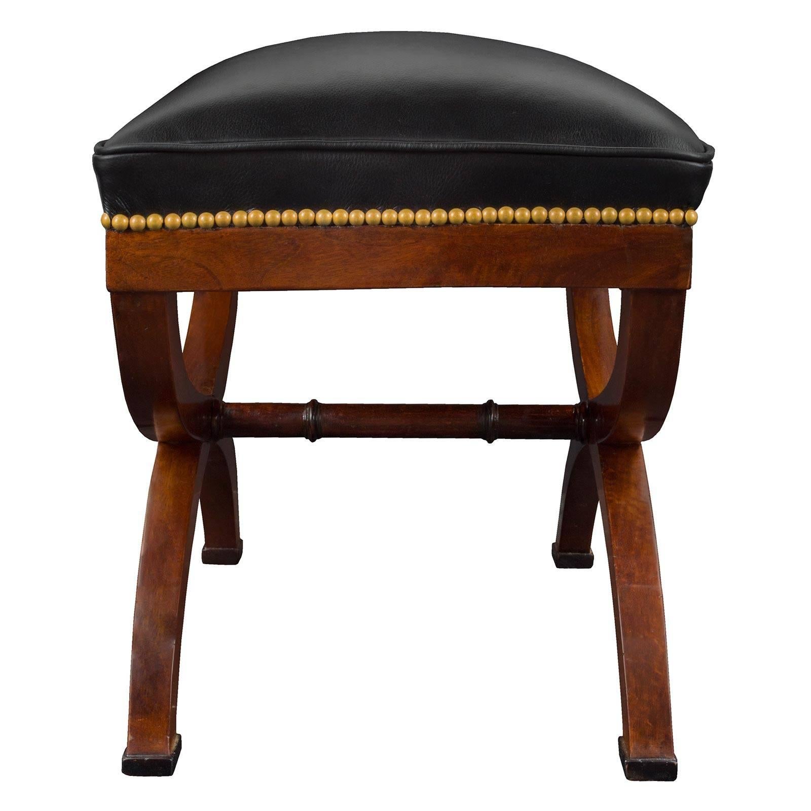 A handsome pair of French early 19th century neoclassical style mahogany and ebony benches. Each rectangular bench is raised on ebony blocks below mahogany ’scrolled legs. The supports are joined by an attractive central turned stretcher. The