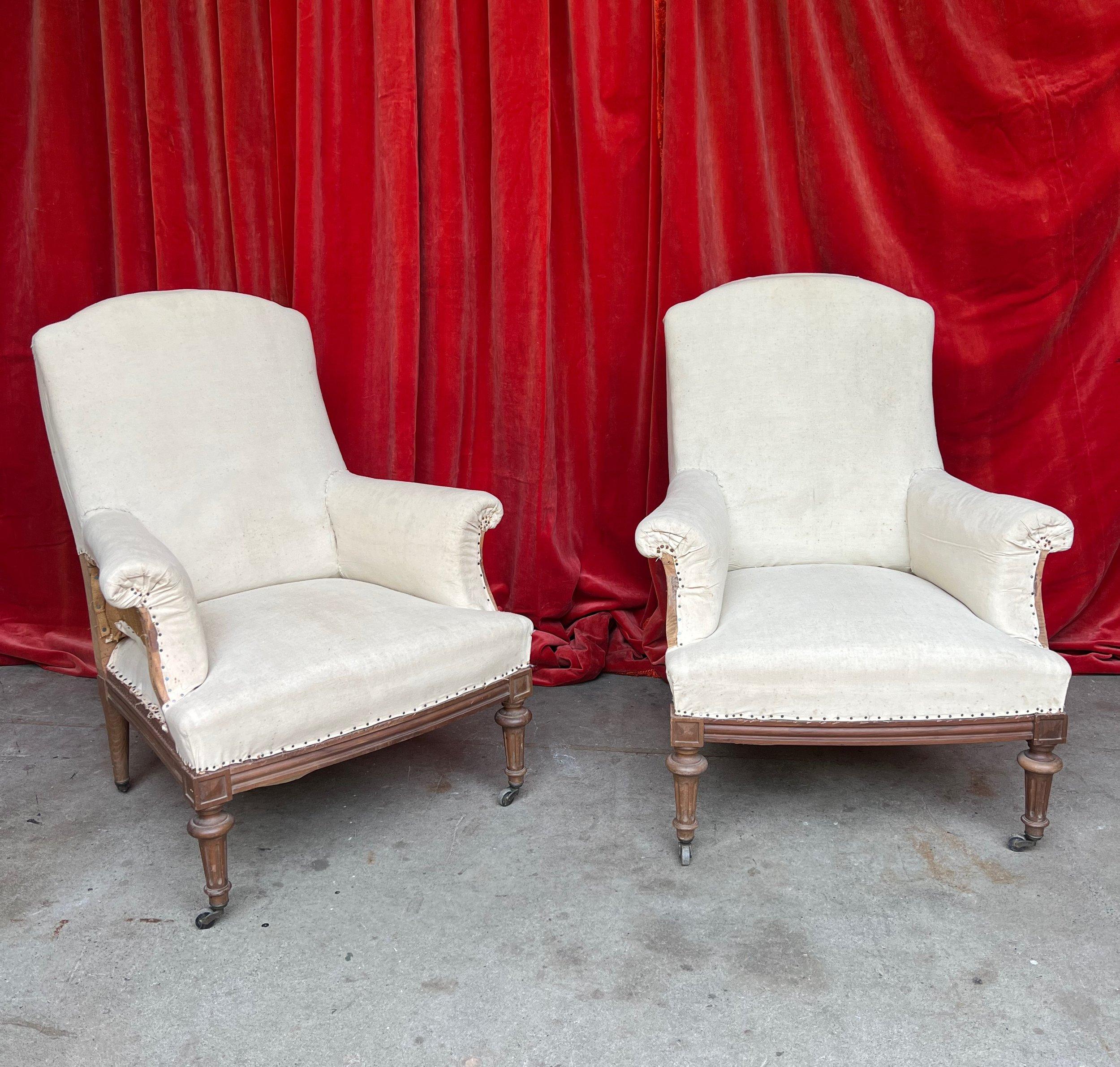 An elegant pair of French Napoleon III armchairs, exuding timeless sophistication and dating back to the early 20th century. These exquisite chairs boast hand-carved fruitwood frames, meticulously crafted with attention to detail that reflects the