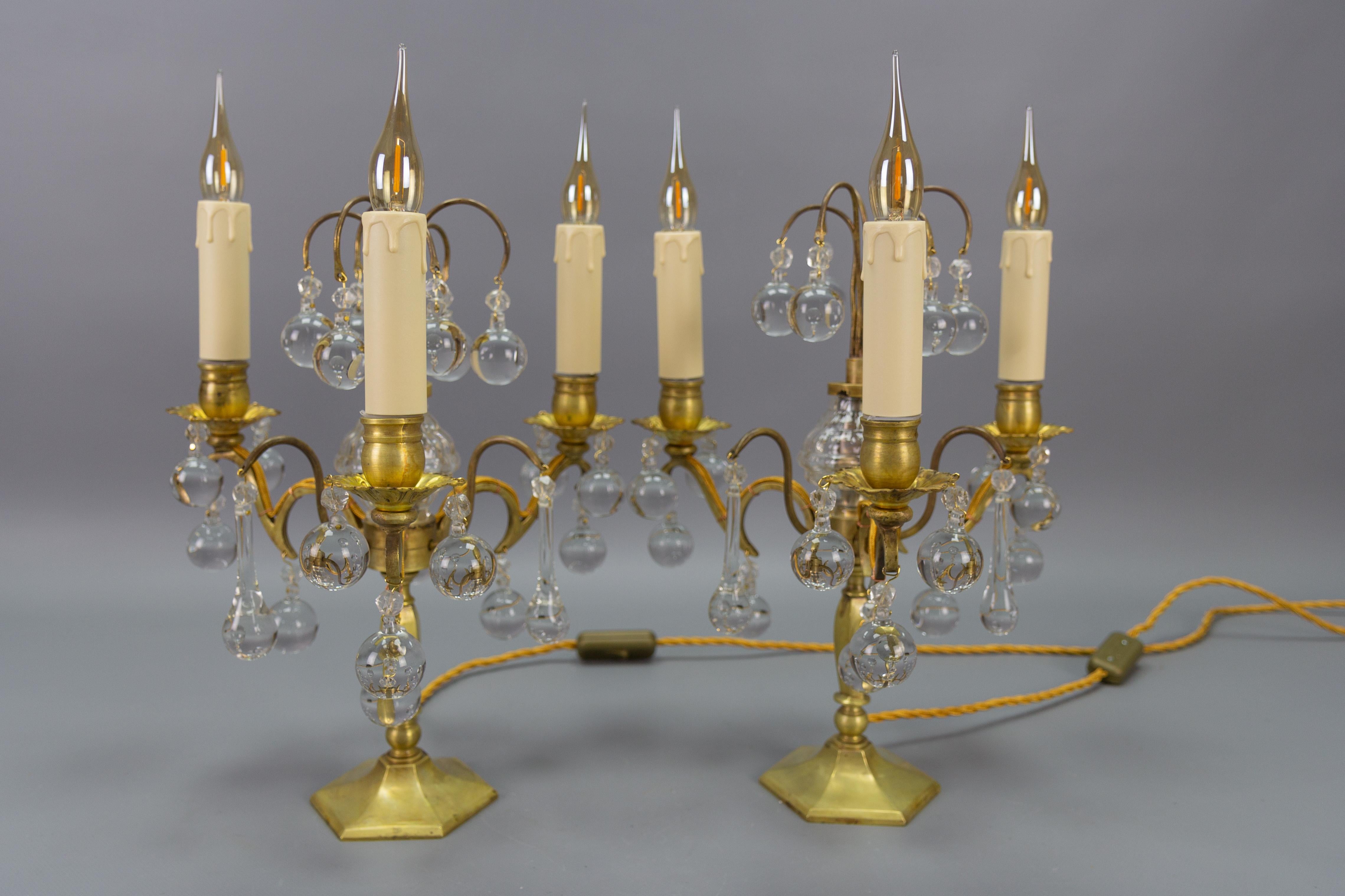 Pair of French brass and crystal three-light girandoles table lamps from circa 1900.
This elegant pair of French antique candelabra table lamps or girandoles are made of brass and are decorated with crystals - balls, teardrop-shaped crystals, and