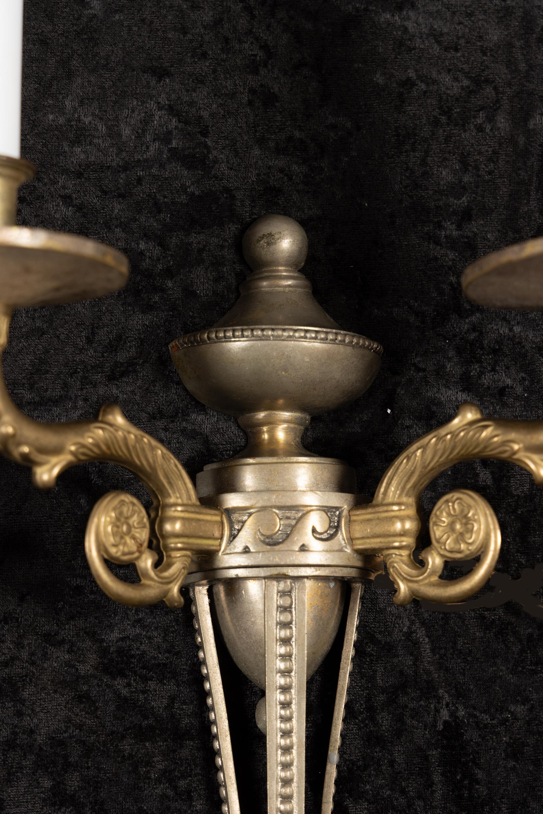 Featuring a beautiful pair of French early 20th century directoire two tone sconces. Each sconce features two scrolling bronze arms with simple bobeches. The body plays host to a silver patina and detailed beadwork. Further details can be found at