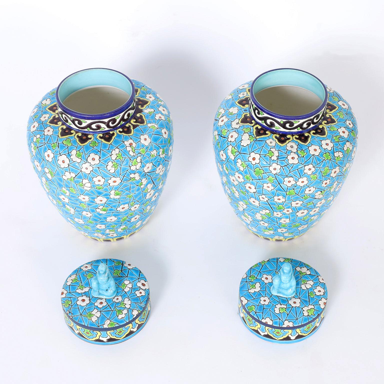 Pair of Art Deco earthenware lidded jars by Emaux de Longwy decorated in enamel underglaze with flowers and clovers over an alluring turquoise mosaic background.