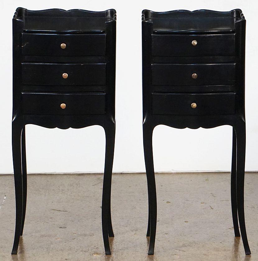 A fine pair of French ebonized (black) bedside end tables or nightstands, each stand featuring a scalloped edge gallery over a frieze of three drawers with brass pulls, apron bottom, and set upon four tapering cabriole legs.

Priced as a pair -