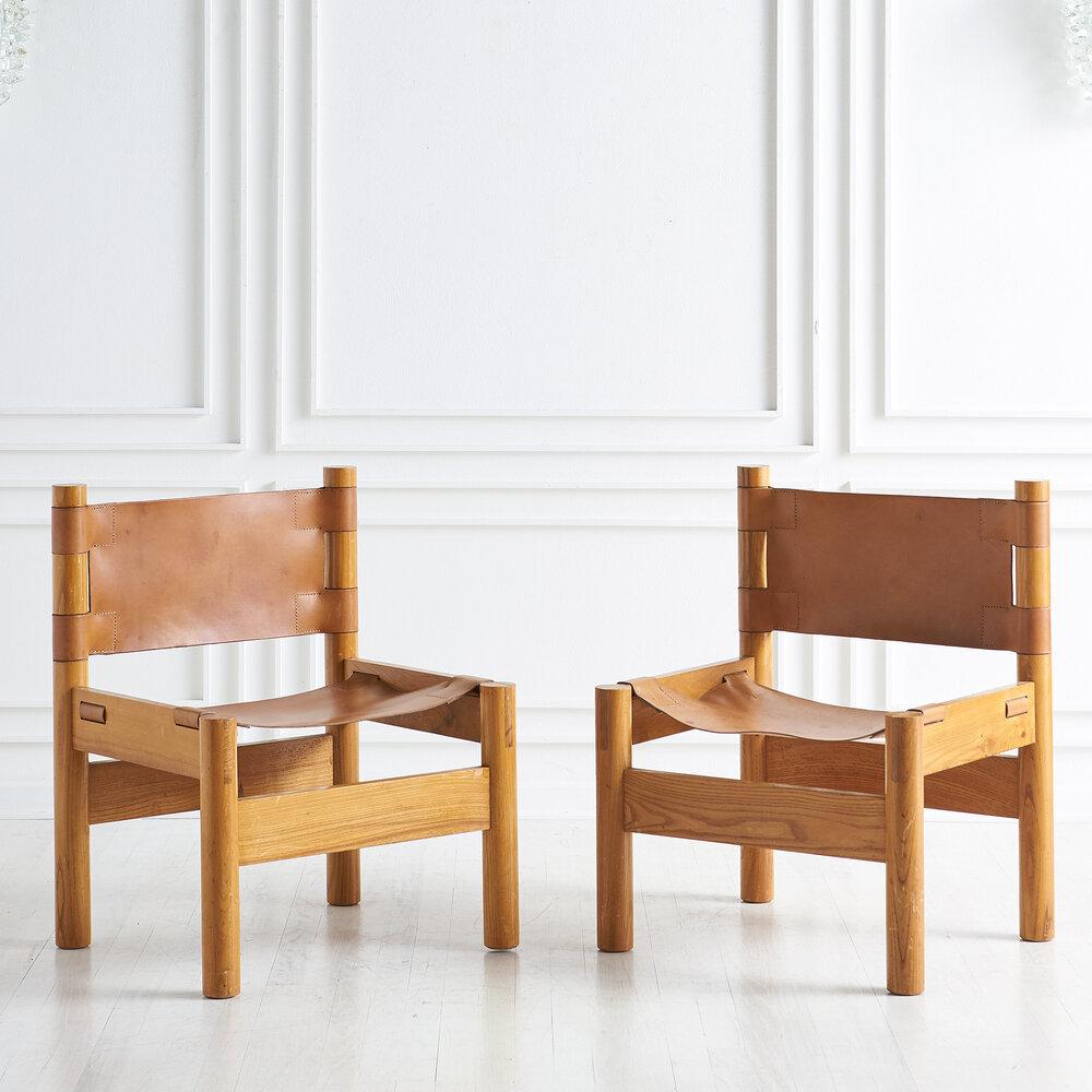 A pair of 1970s French leather lounge chairs. Featuring an elm wood frame and thick, cognac saddle leather.

Dimensions: 24