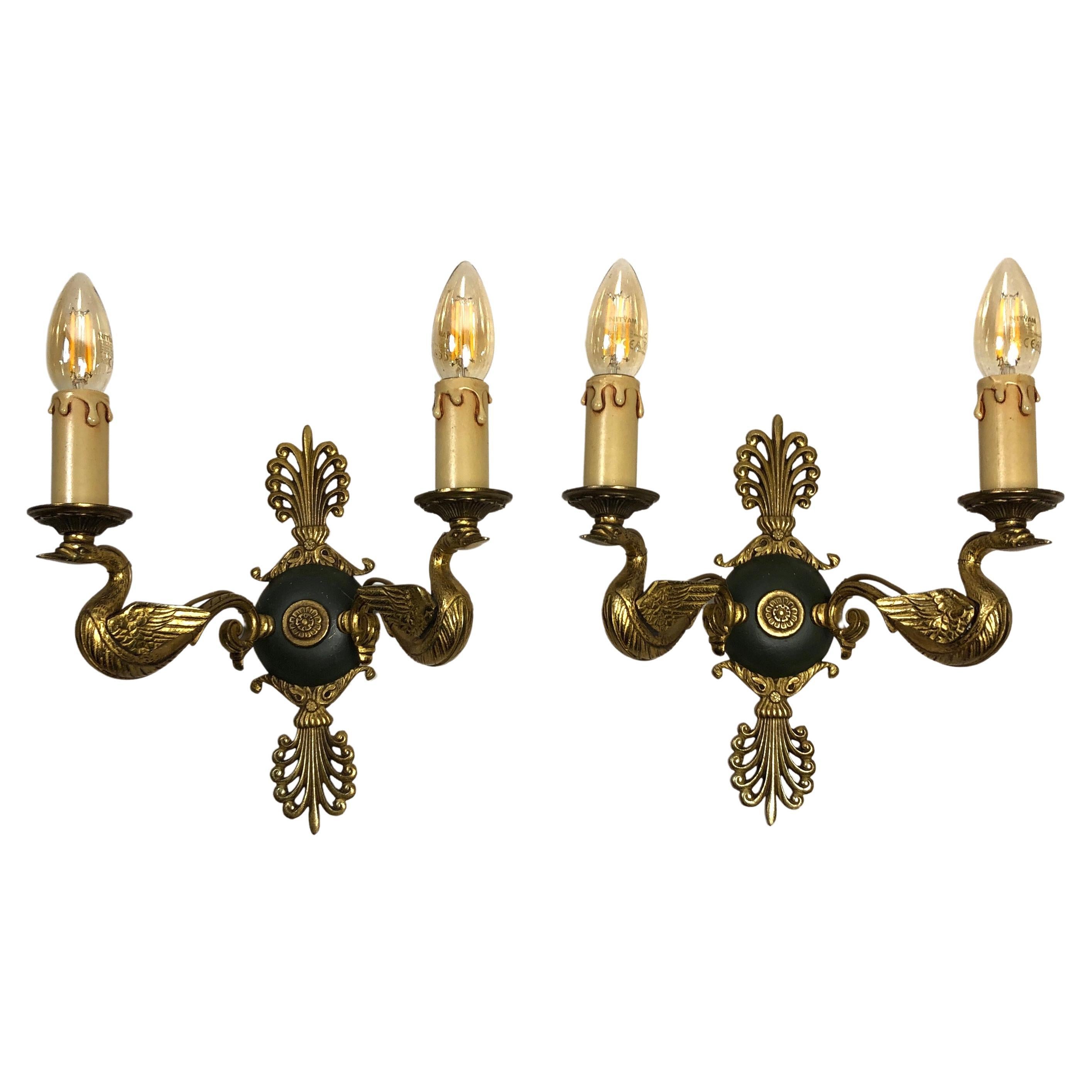 An exceptional pair of brass Empire two-light sconces from early 20th century, France. This pair is designed with a swan motif. The two brass arms are fashioned out of swans with the brass bobeches and candle covers resting on each birds' head.