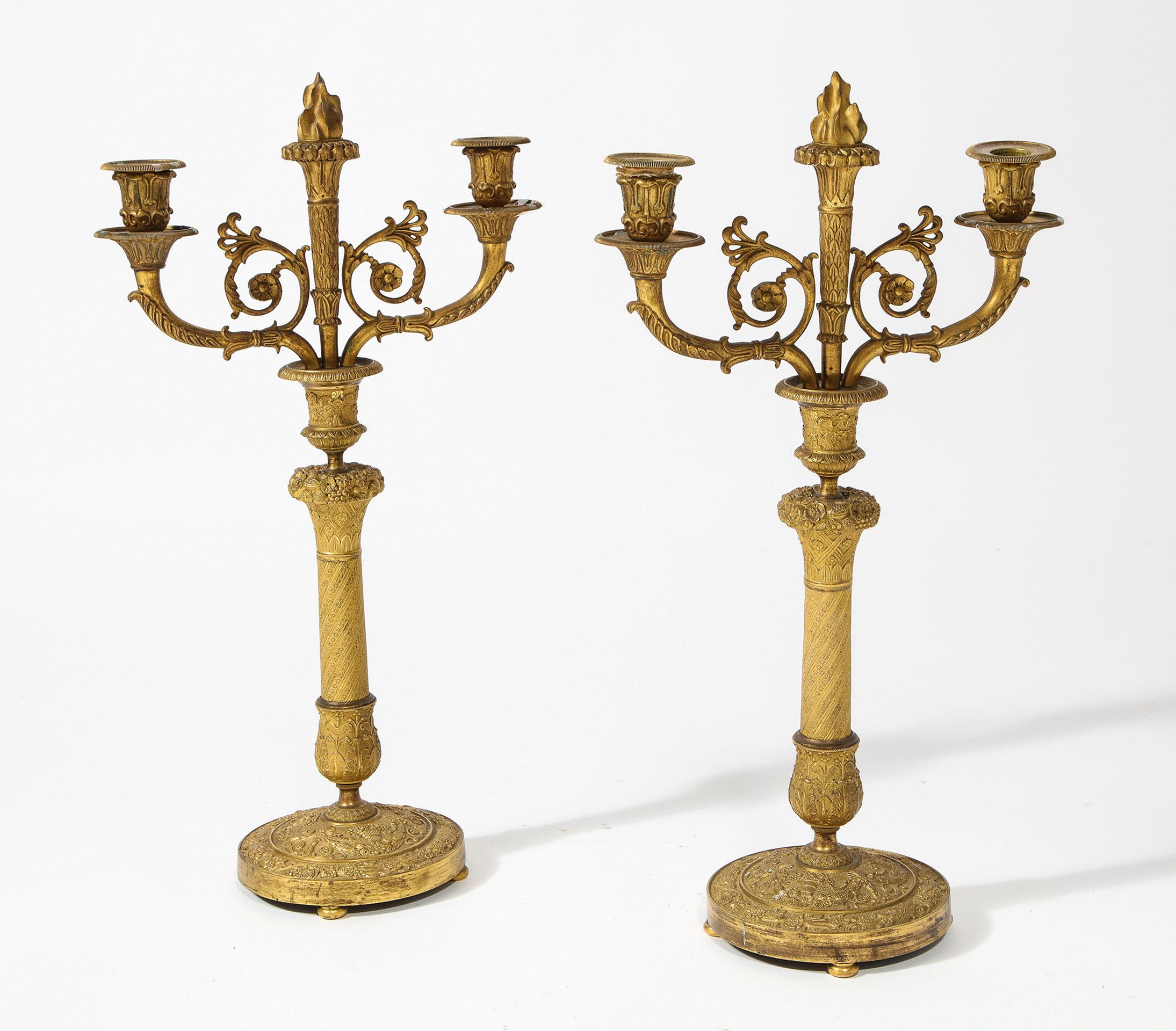 Mit einer abnehmbaren zentralen Bronzeflamme, flankiert von stilisierten Kerzenhaltern, auf einem geprägten Stiel mit ähnlichem Sockel.