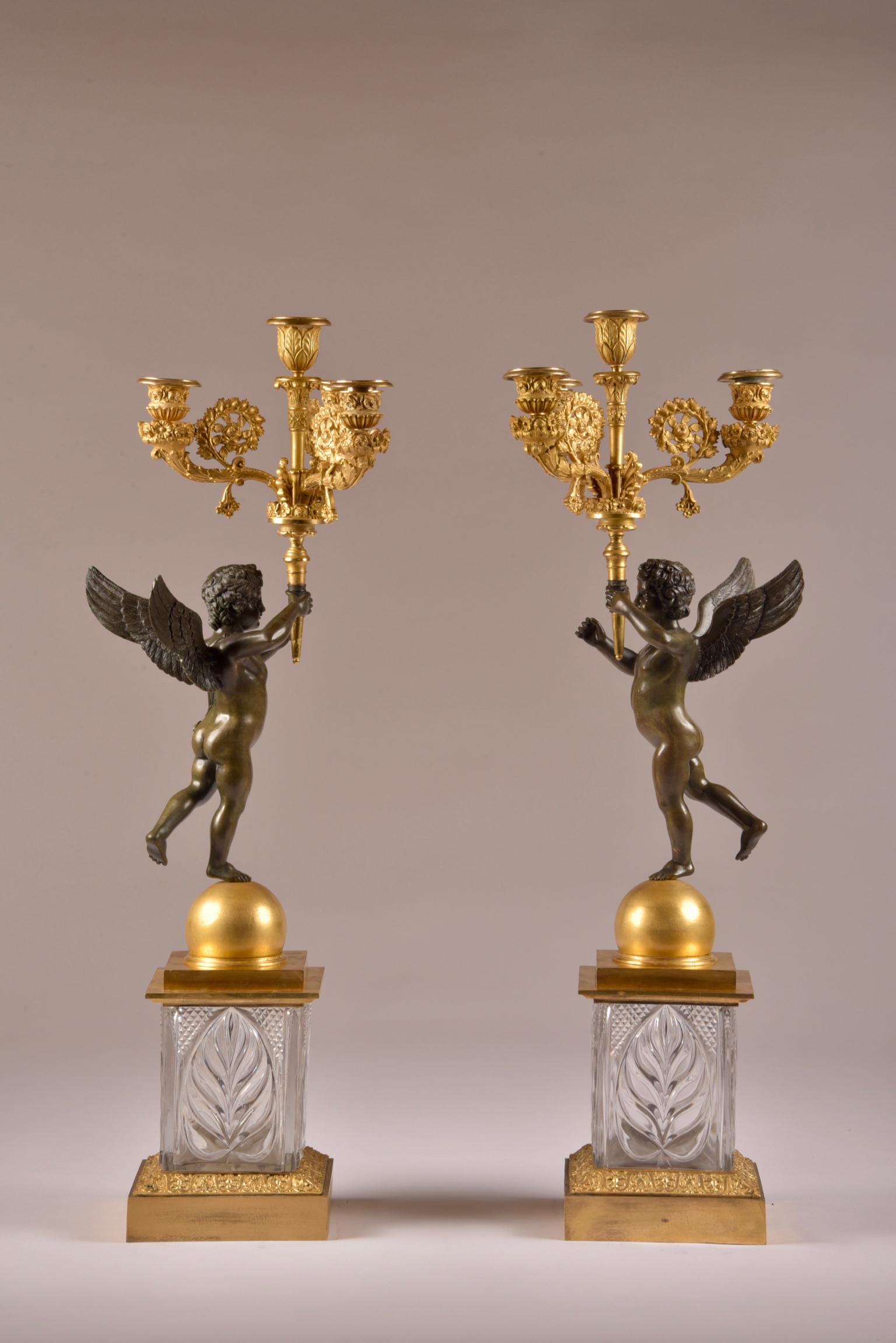 A stunning rare pair of Empire four-light gilt bronze figural candelabras, of French origin, circa 1810. 
A beautiful pair of candlesticks issue a torch, held by putti balancing on a round sphere and in very special on crystal glass base.
    