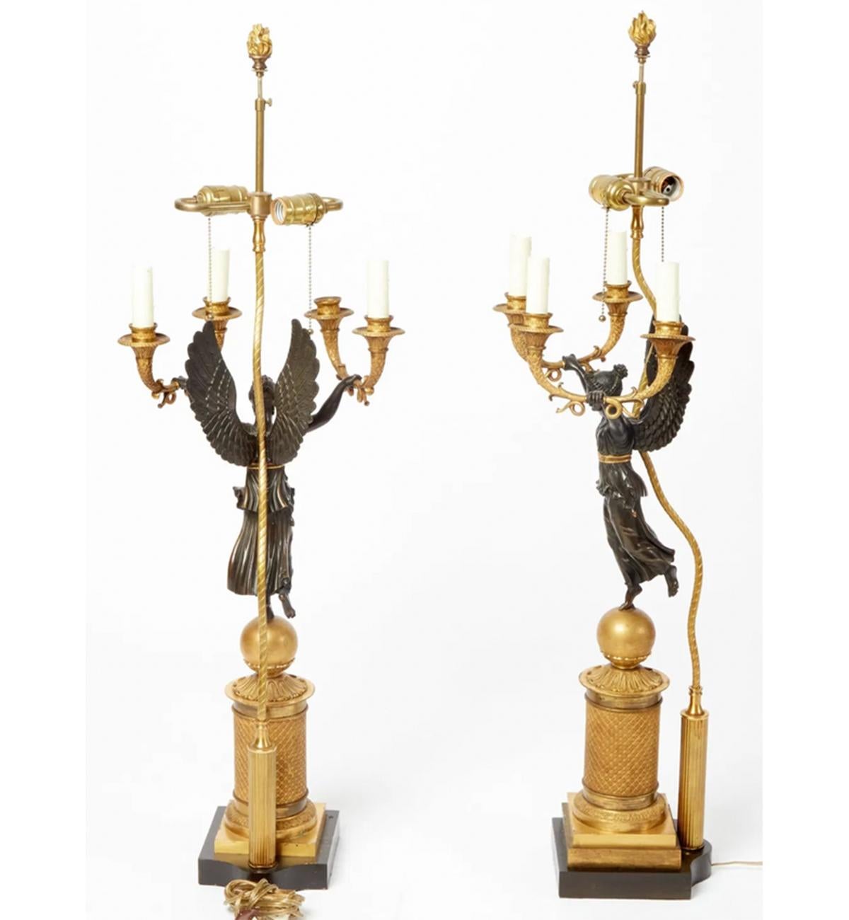 Coppia di candelabri figurativi in bronzo patinato e dorato dell'Impero francese trasformati in lampade da tavolo

Ogni stendardo ha la forma della Vittoria Alata

Data: circa 1810

Altezza complessiva 39 pollici;

altezza del candelabro 27