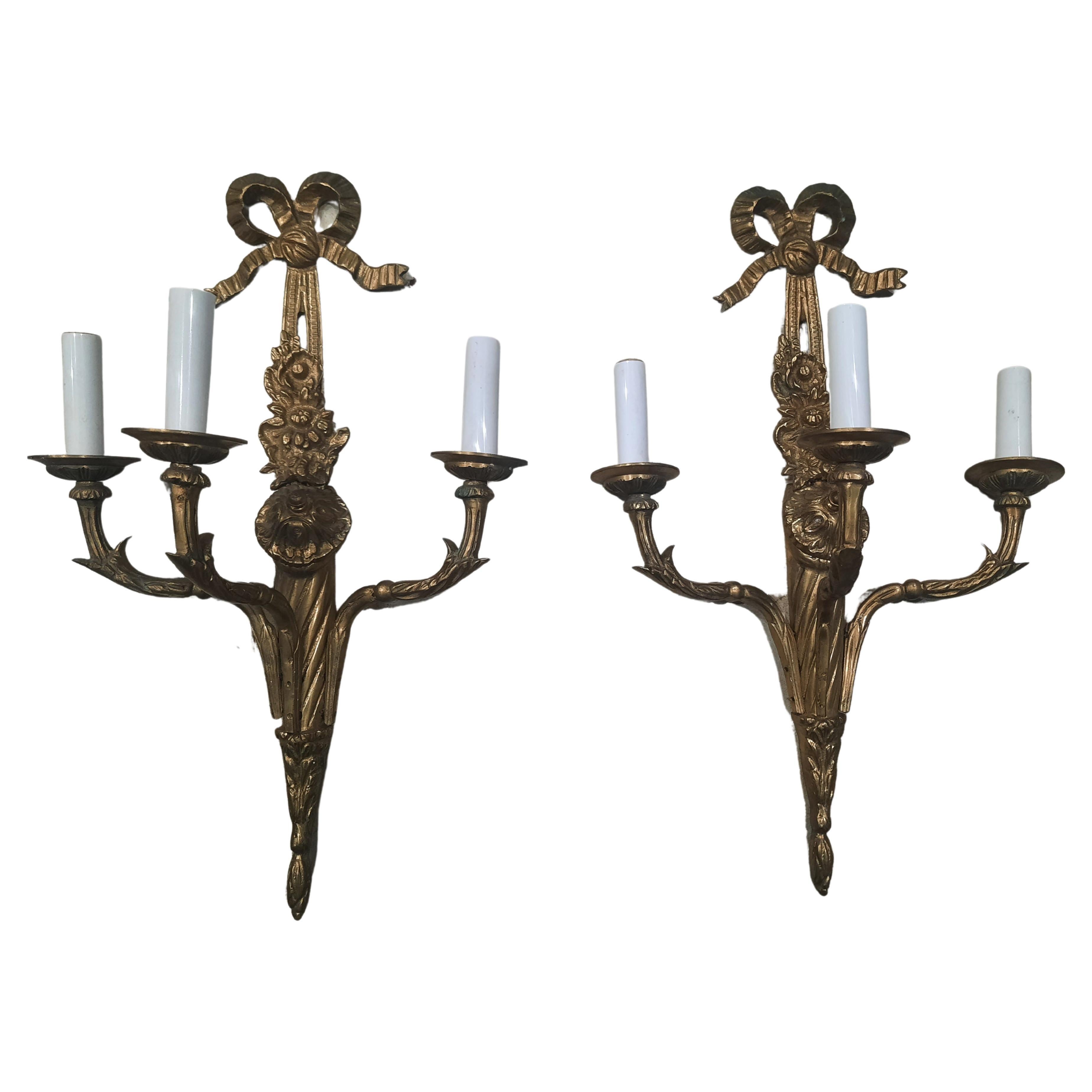 This pair of antique gilt bronze appliqués are finely detailed, and feature neoclassical motifs including bowknots and acanthus leaves. They are electric powered with completely newer sockets.
Measures 13