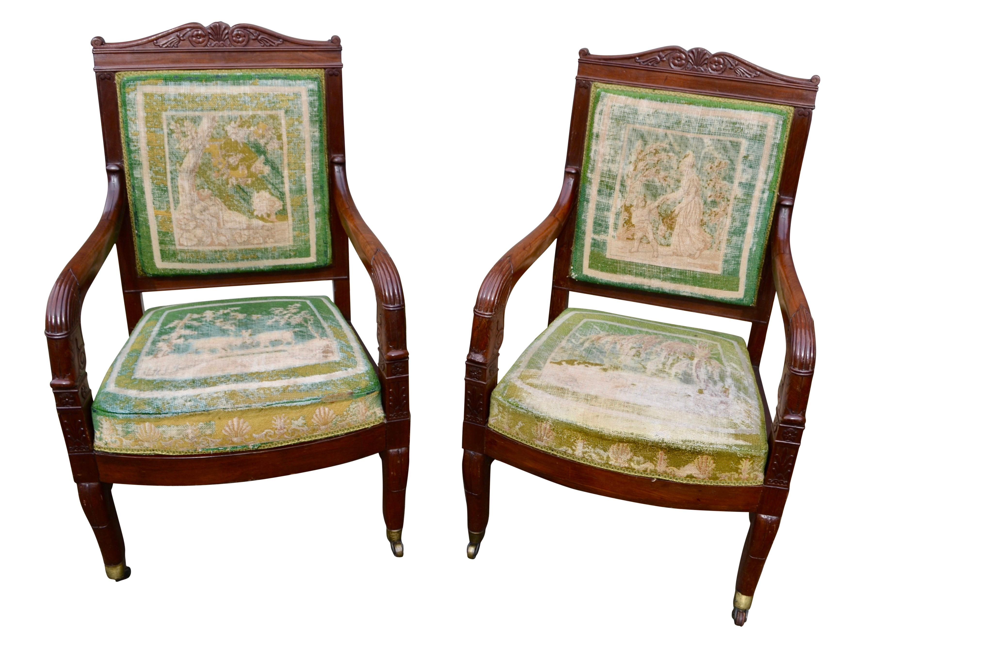 A classic pair of French Empire period open armchairs  each with a square back topped by a bow shaped carved frieze featuring folliate rosettes and downscrolled arms. Where the arms join the chair rail there are carved anthemians and palmettes.