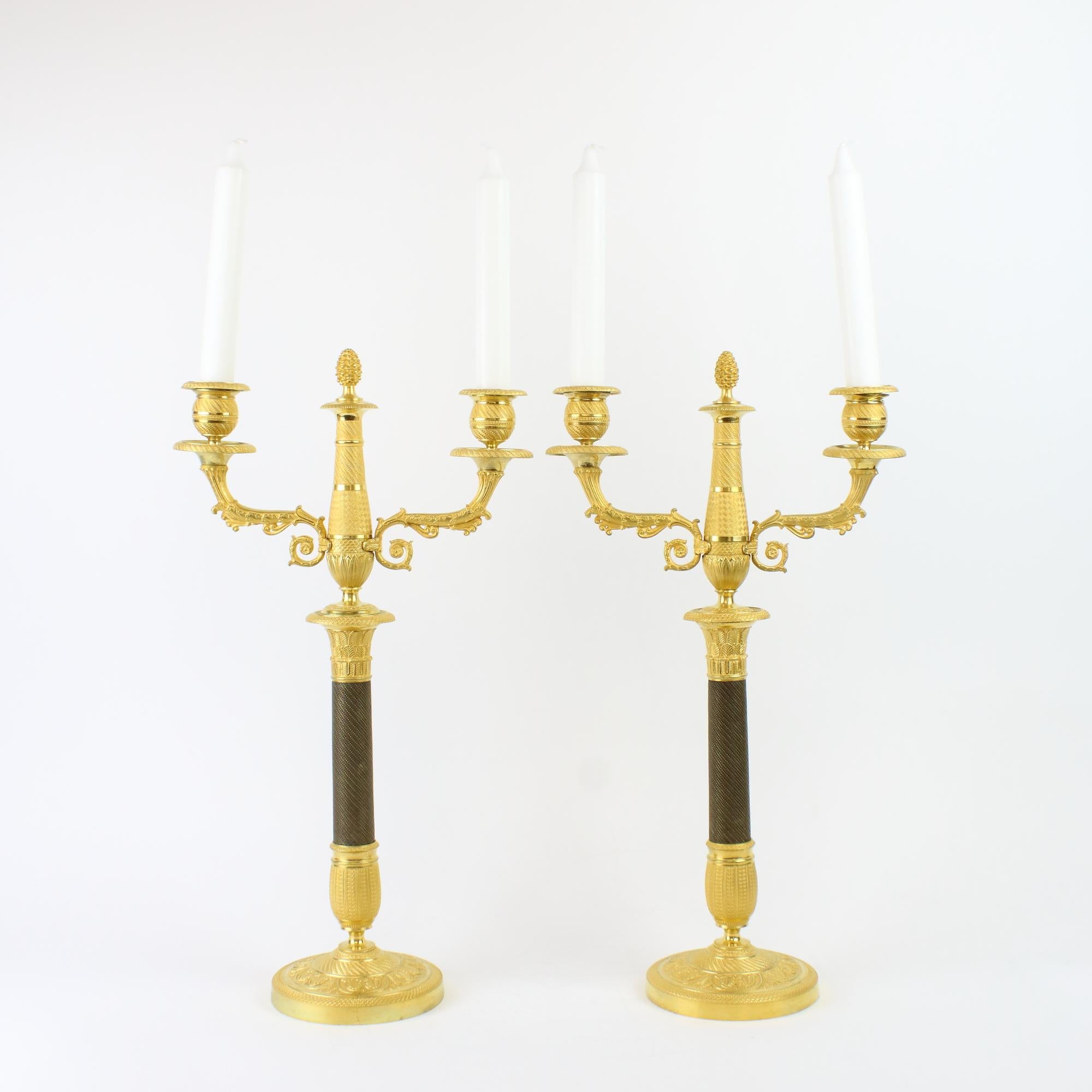 Pair of French Empire Neoclassical One-/Two-Light Patinated and Gilt Bronze Candelabra

A tapering, partially patinated pearl frieze bronze stem on an ovoid gilt bronze guilloche socle standing on a circular plinth decorated with foliage and