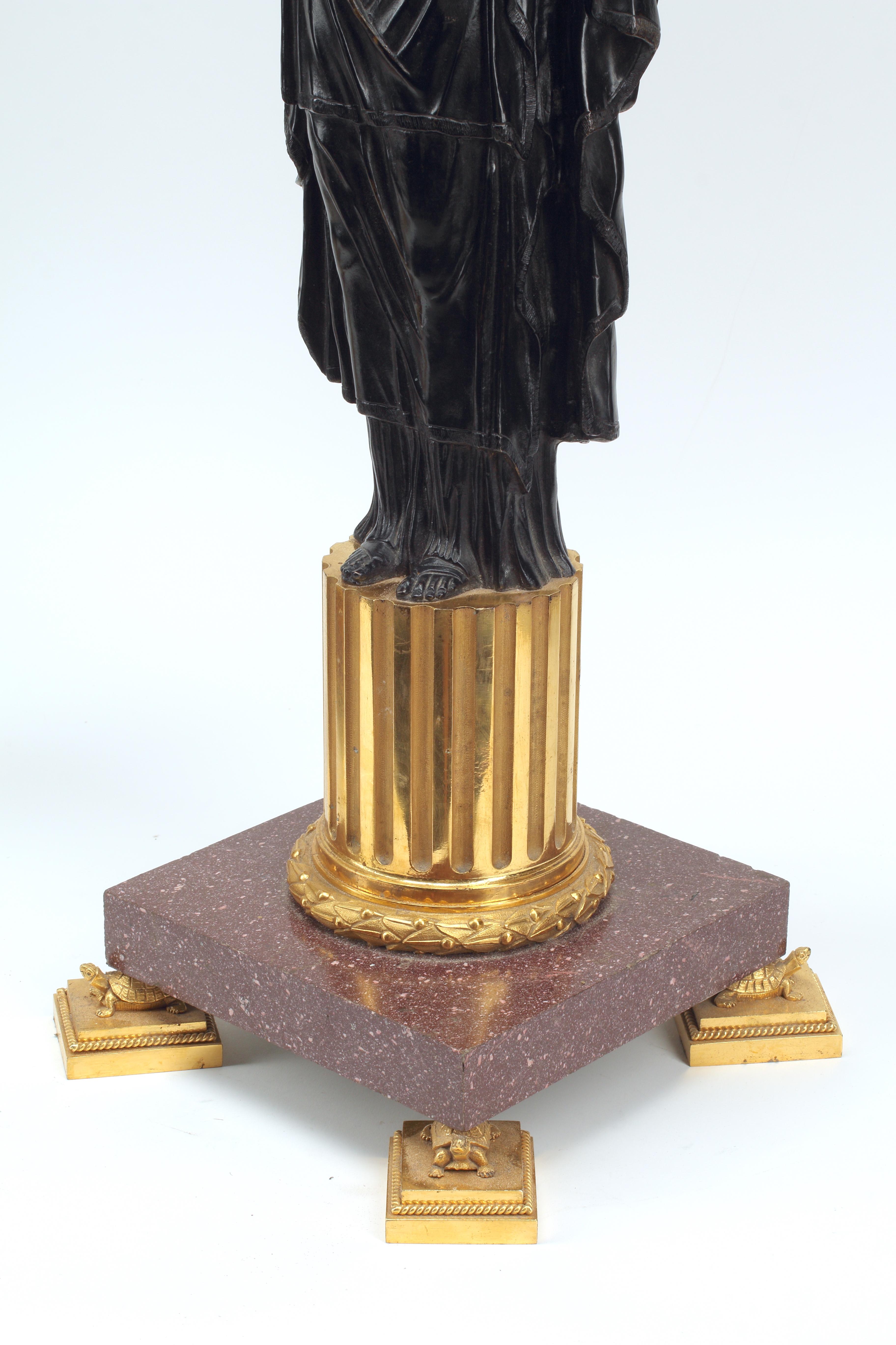 This impressive pair of gilt and patinated bronze candelabra is a quintessential example of the French empire style. Drawing from Greco-Roman influence, each candelabra features a central female figure in patinated bronze draped in intricately