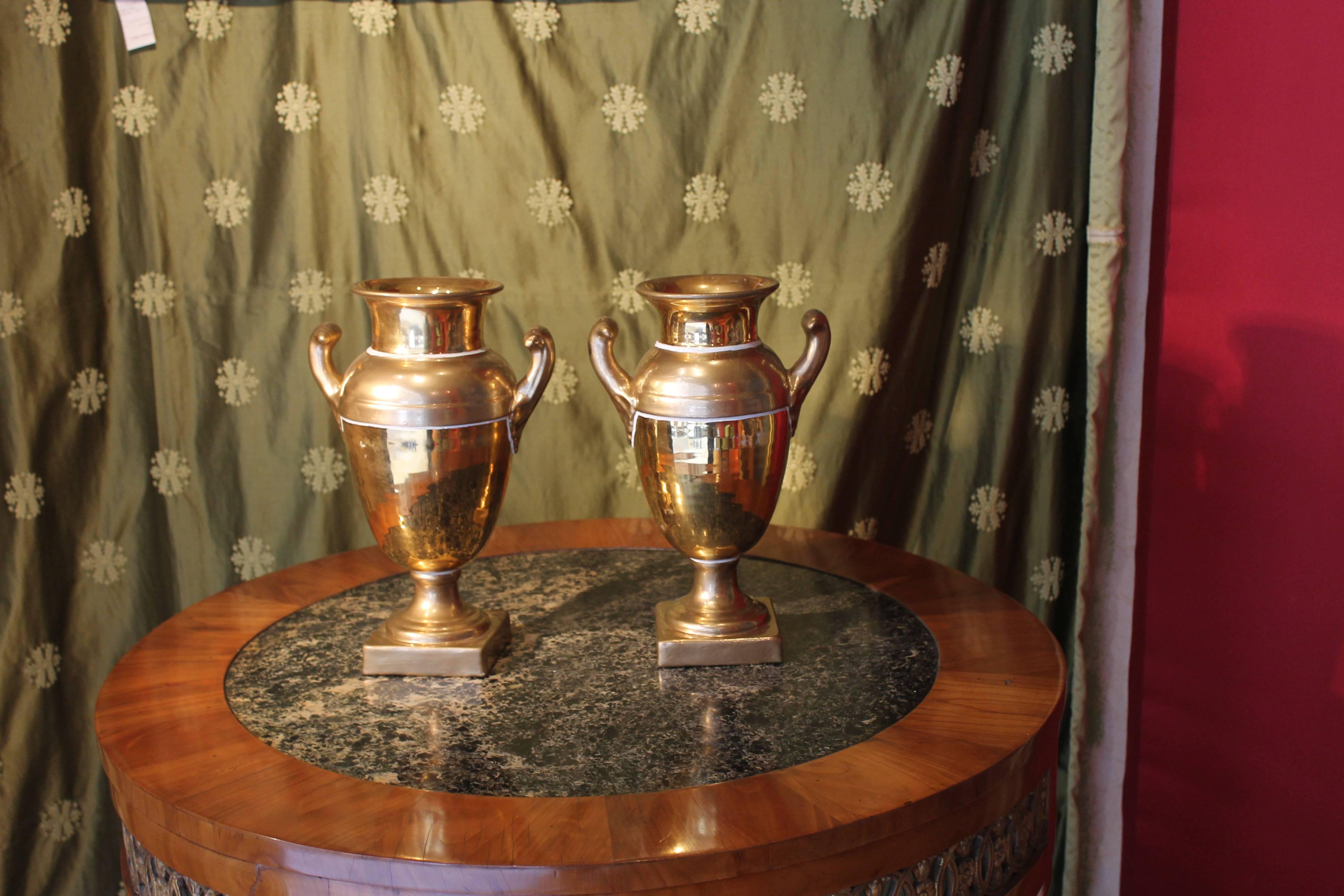 Zwei balusterförmige Vasen aus französischem Empire-Porzellan des 19. Jahrhunderts mit zwei Henkeln. Der Korpus jeder Vase besteht aus zweifarbigem Gold, das in außergewöhnlicher Weise mit mattem und glasiertem Gold bearbeitet ist. Die Vasen haben