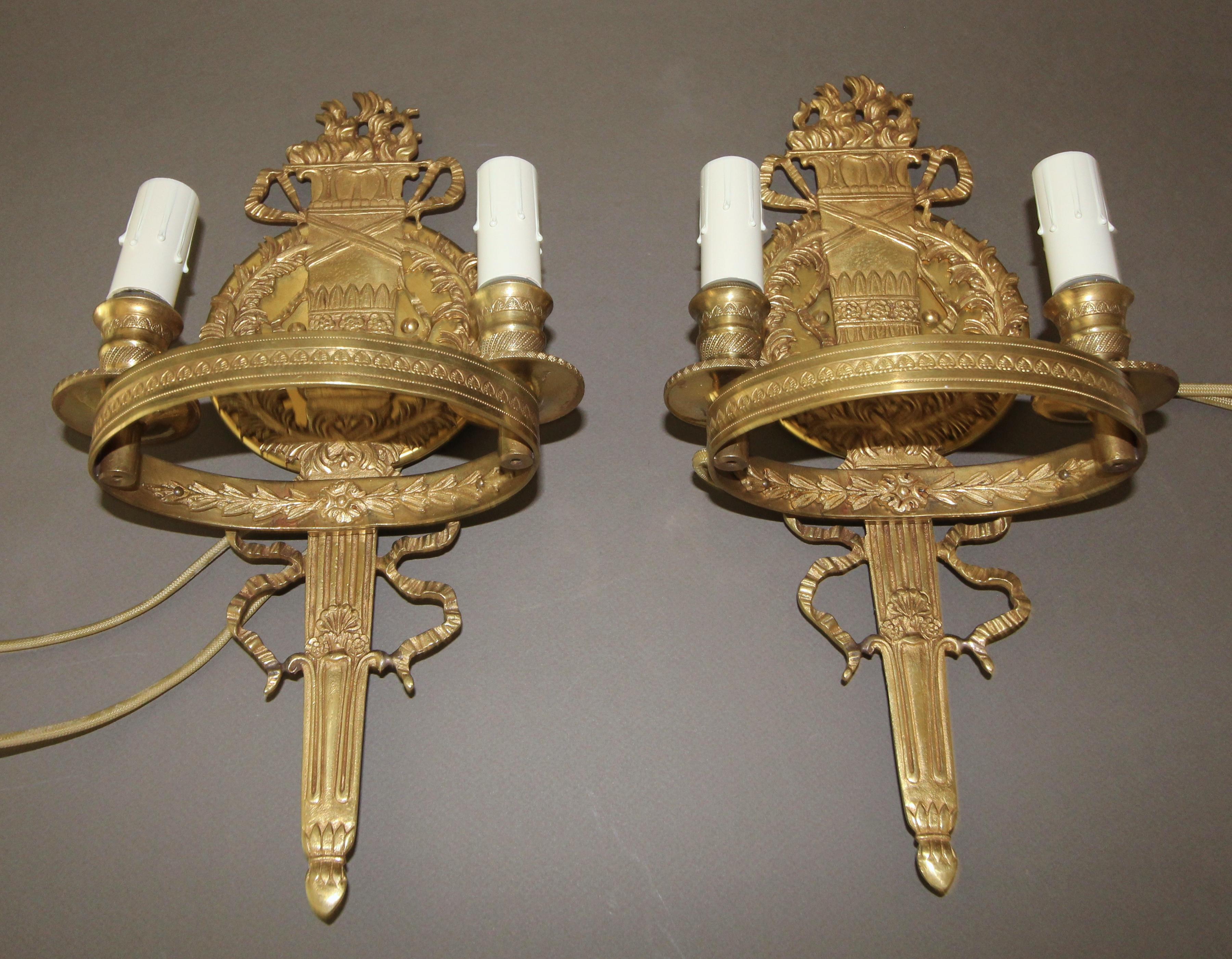 Pair of nicely detailed French Empire style two-arm wall sconces with central flame and torch motif. Newly wired for US with back plates added for US installation.