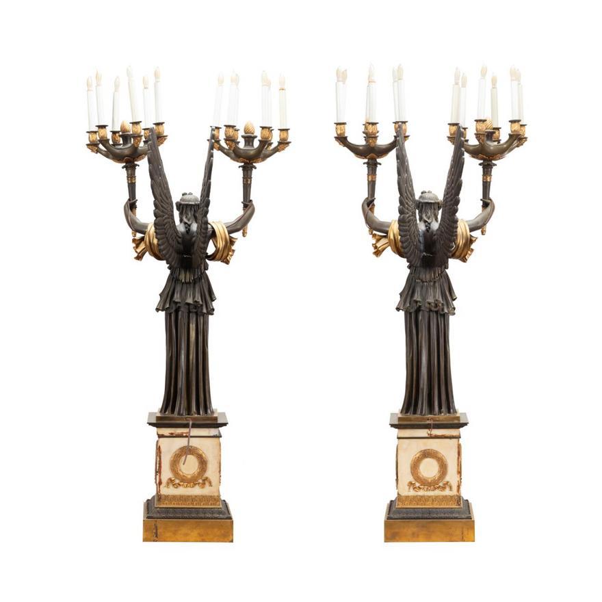 A Very Fine & Spectacular Pair of French Empire style Bronze & Bronze Dore 12 light Figural Candelabra, late 19th Century, each depicting a standing winged Victory with outstreached arms holding two torches. Each supported on a cream colored marble