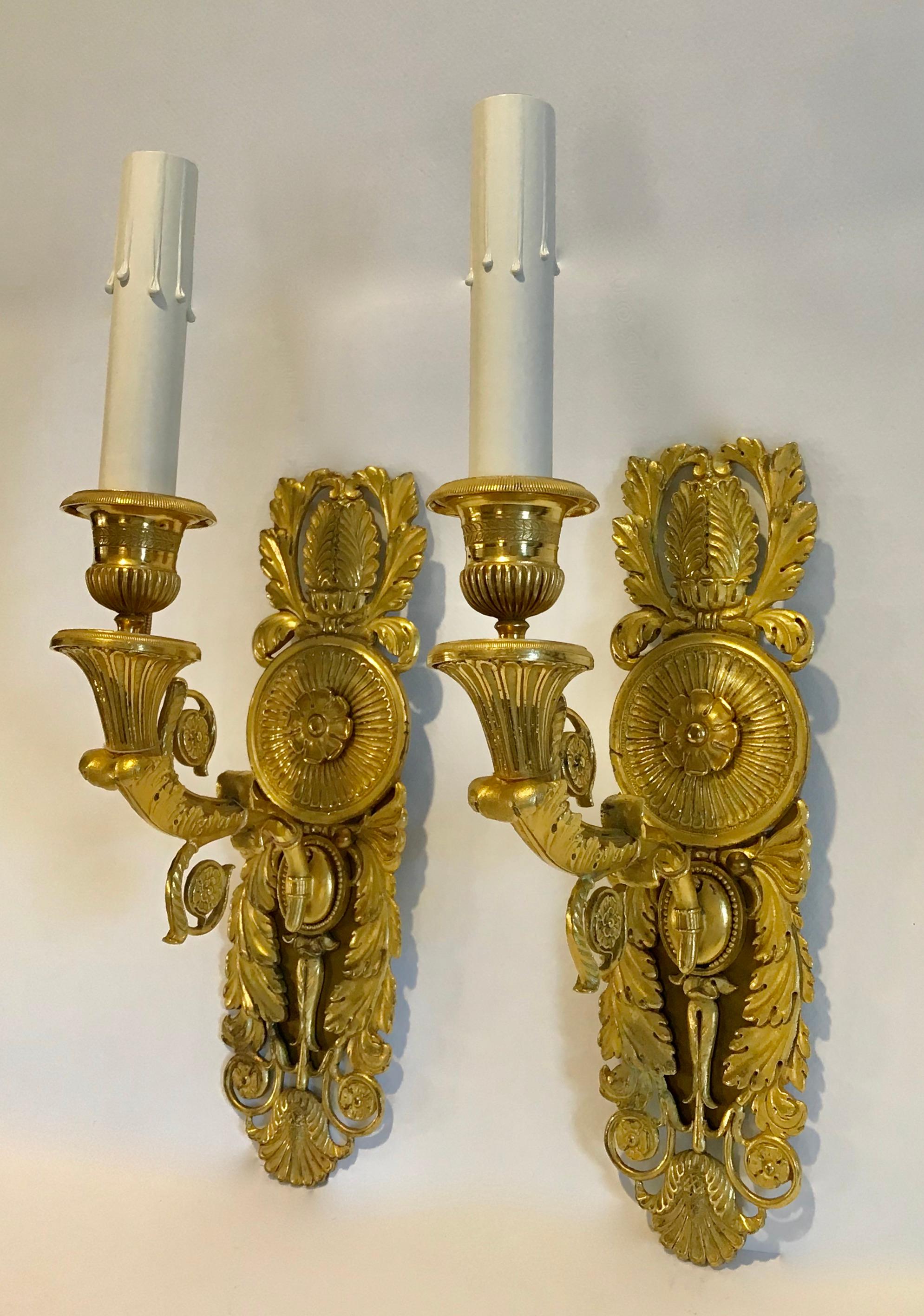 Pair of dore gilt bronze French Empire style single arm wall sconces. Exceptionally well chased and detailed. Newly wired for US installations with French style rayon covered exterior wiring. Each sconce uses a single 40 watt recommended max 