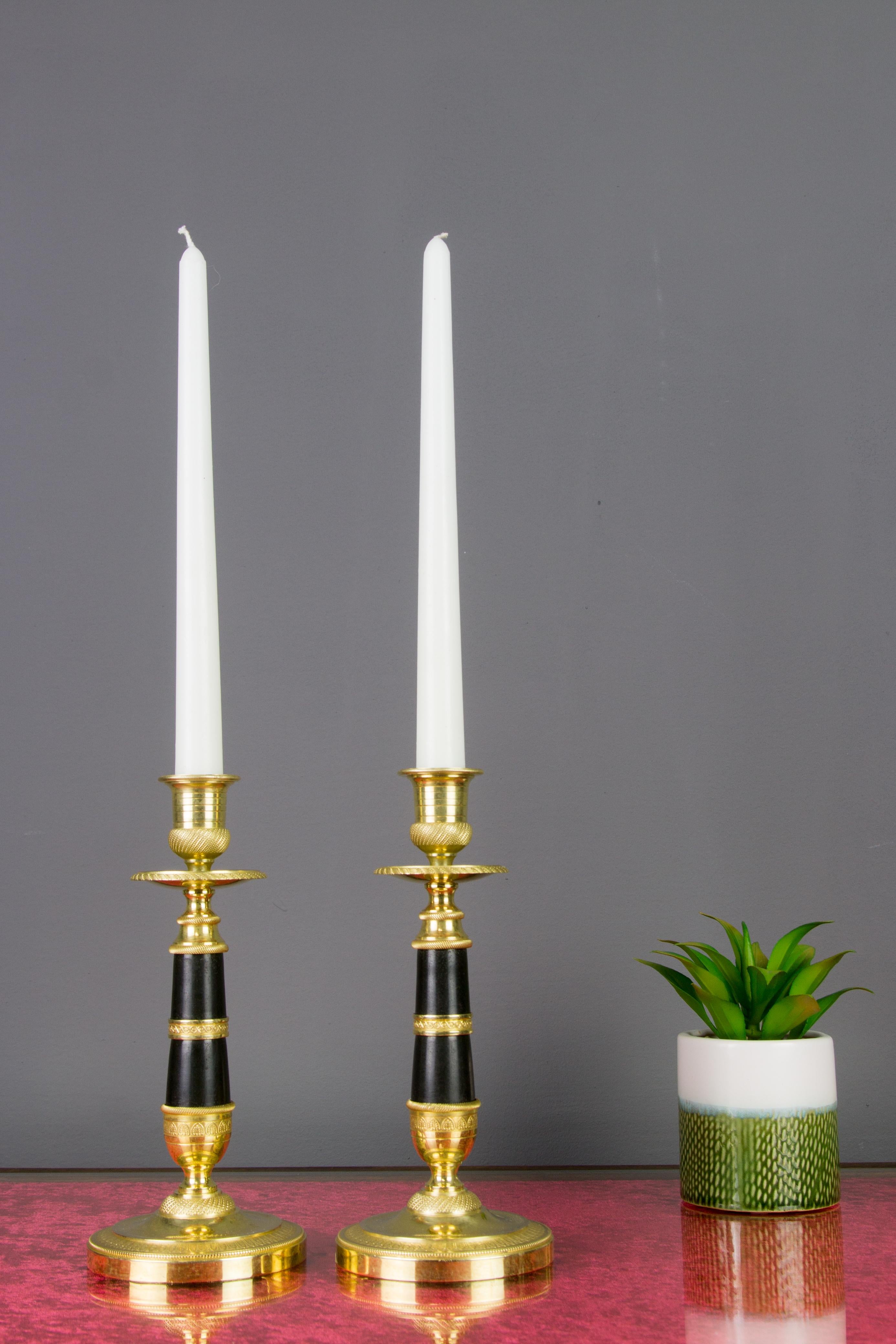 Very nice pair of French Empire style gold-plated, patinated and burnished bronze and brass candlesticks. Each candlestick features finely engraved decors and is raised on a round ornate base.
Dimensions: height 20.5 cm / 10.43 in, diameter of the