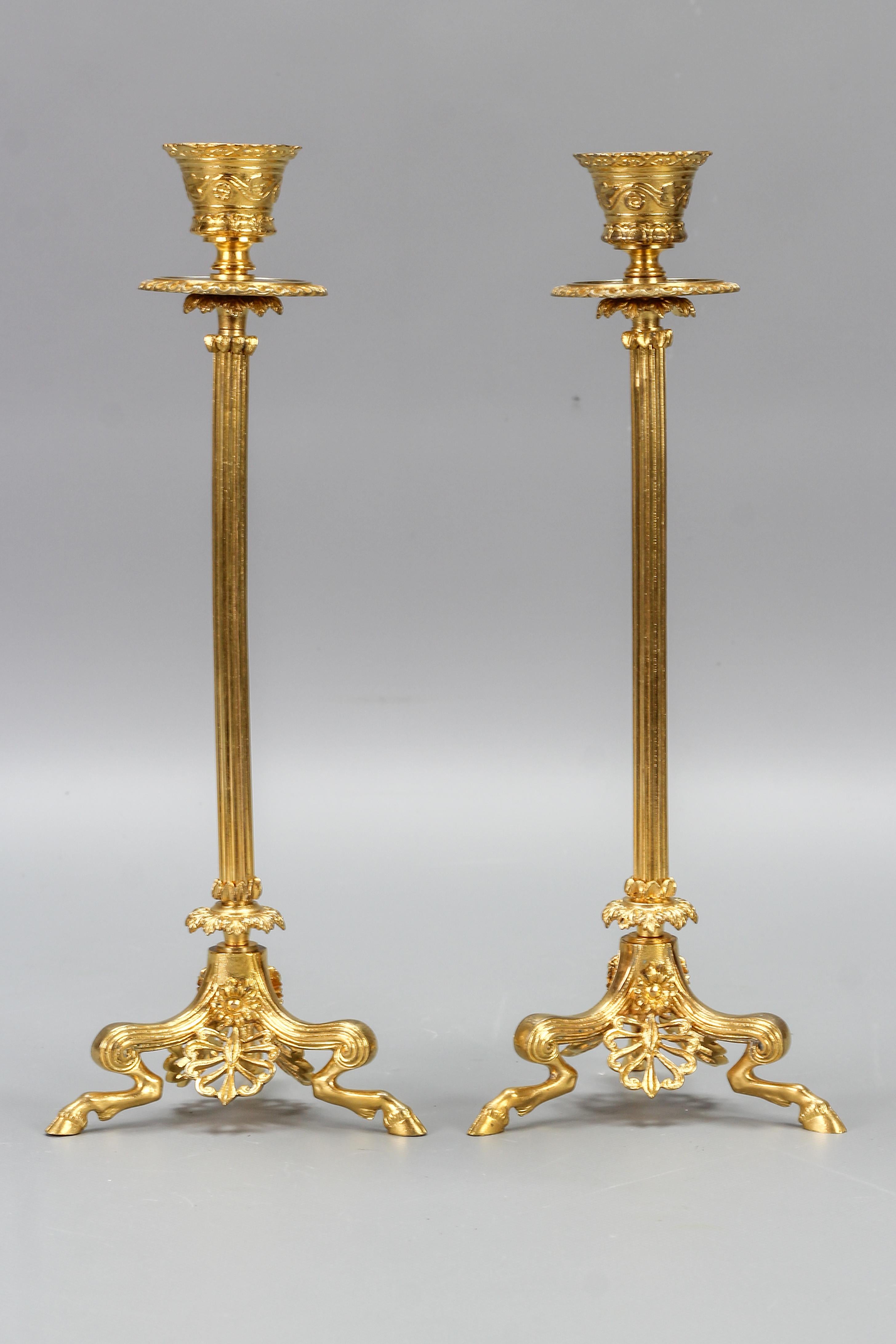 Pair of French empire style gilt bronze candlesticks on hoofed faun feet, late 19th century.
A pair of fine French Empire-style gilt bronze candleholders. A fluted column rises on three cloven-hoofed hocked faun legs and feet. These antique