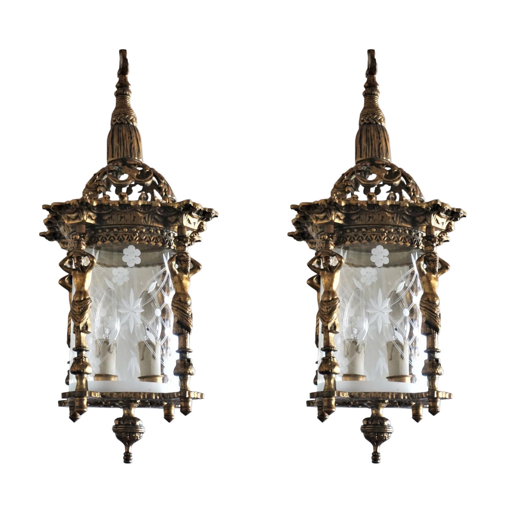 A pair of Empire style cast gilt bronze two-light candelabra lanterns with cut glass cylindrical shade surrounded by four figurine columns, France, late 19th century.
Both lanterns are in very good condition, gorgeous aged patina to bronze,