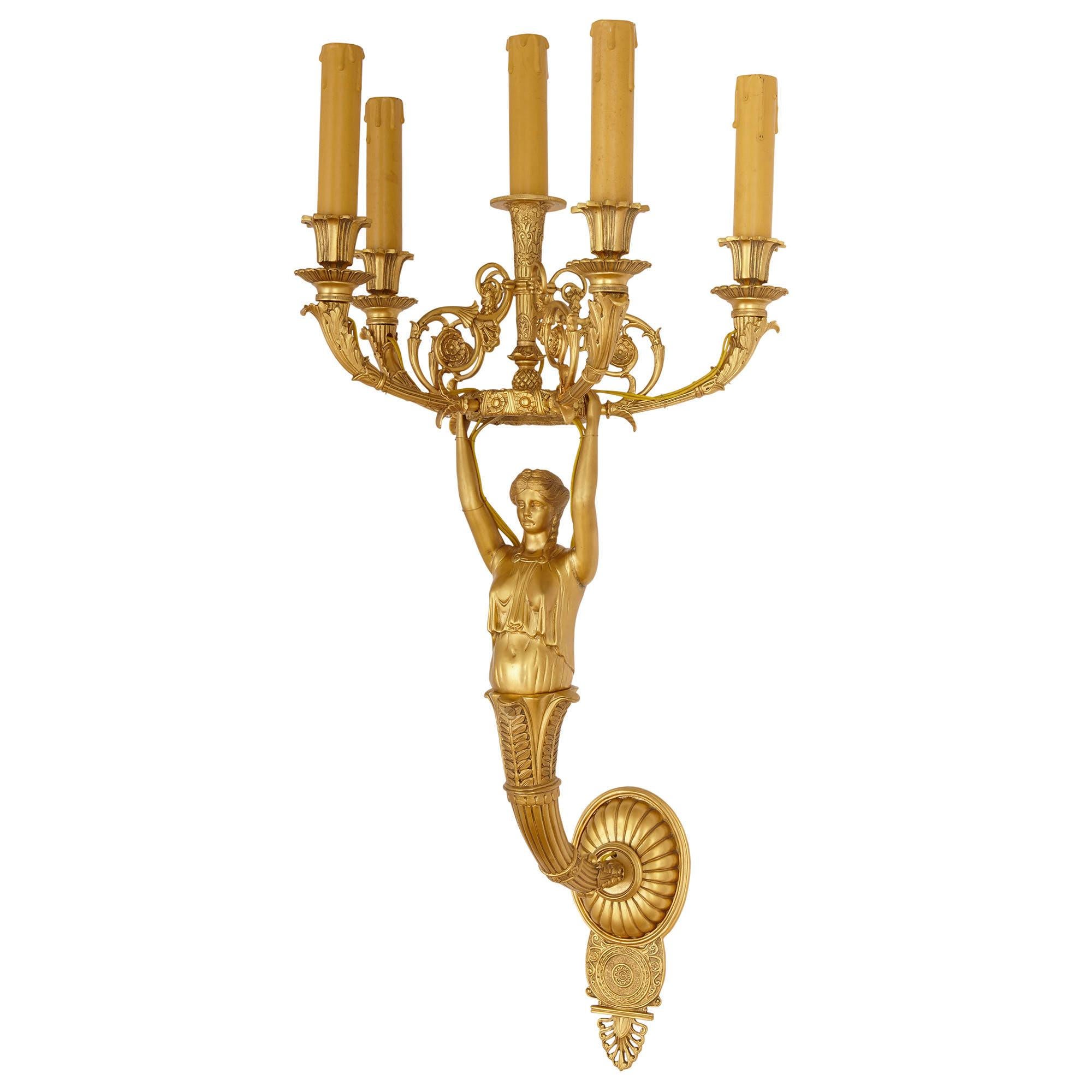 Pair of French Empire style gilt bronze sconces
French, 20th Century
Measures: Height 88cm, width 38cm, depth 35cm

This elegant pair of sconces is wrought from gilt bronze in the French Empire style. Each sconce features five scrolled branches,