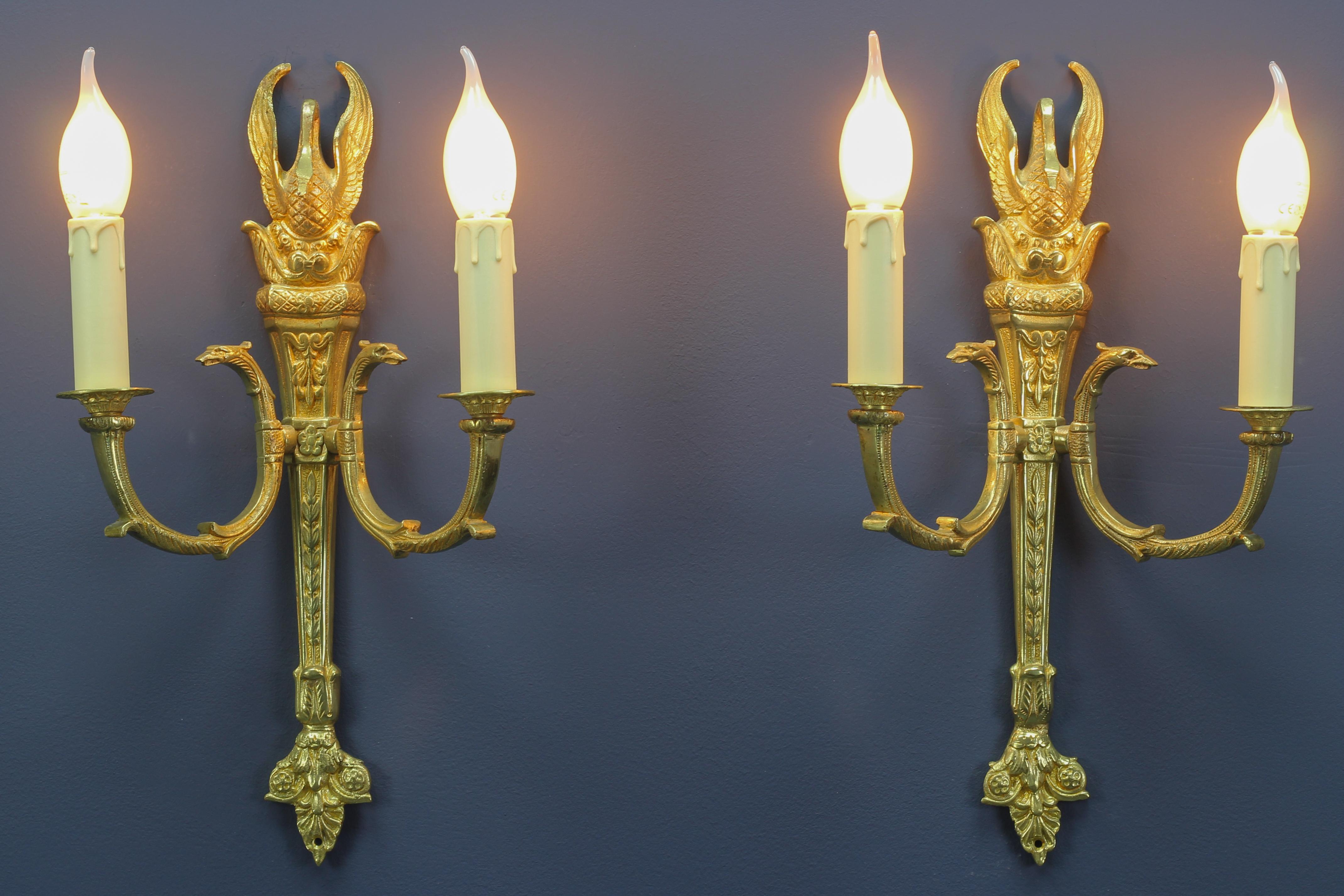 A pair of French Empire-style gilt bronze sconces. These beautiful wall lights are richly decorated with bronze details like flowers, leaves, swans, and griffin heads.
Each sconce has two arms and each with a new socket for an E 14 size light
