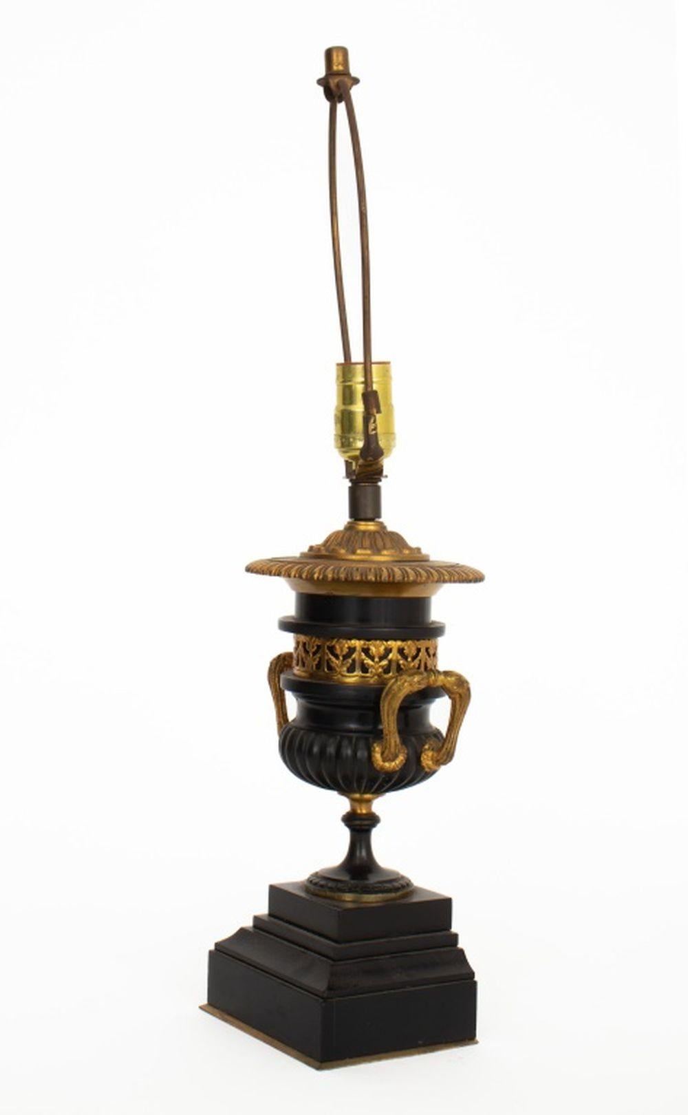 Coppia di lampade a forma di urna in stile Impero francese, montate su metallo dorato ed ebanizzato, ciascuna con due maniglie e montate su una base a gradini. 21,5