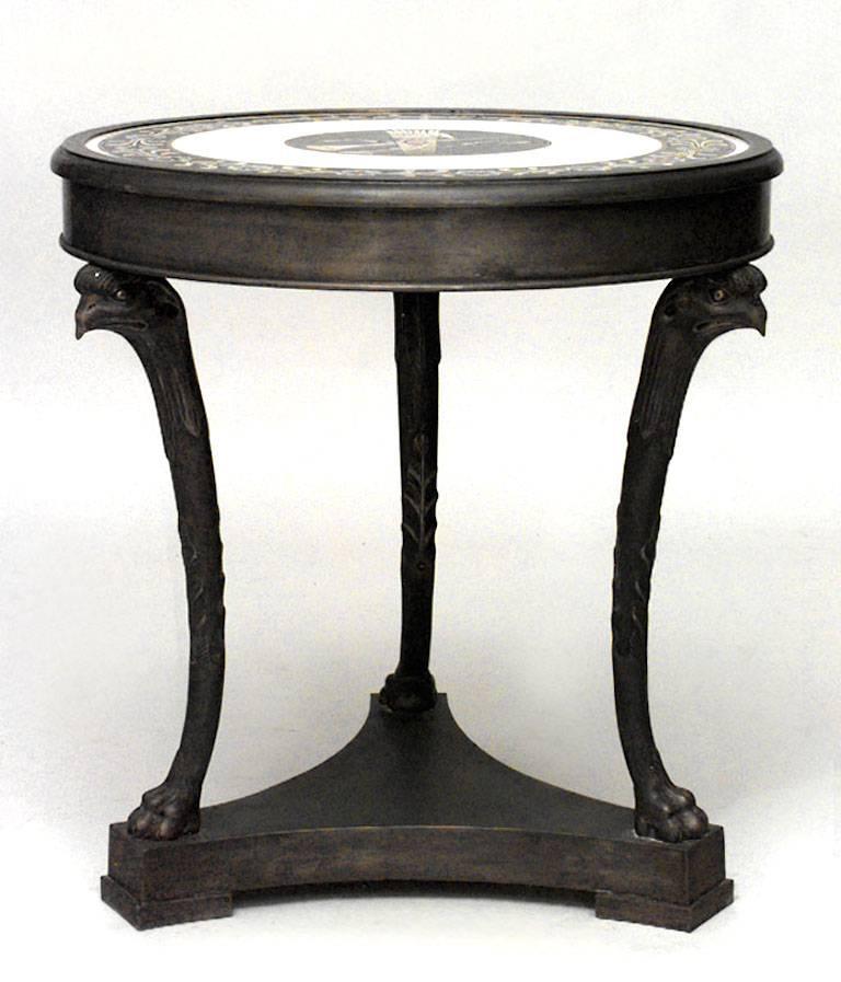 Paire de tables guéridon de style Empire français, rondes, en bronze, à trois pieds, avec têtes d'aigle, plateau en marbre incrusté et base à plate-forme triangulaire.
 