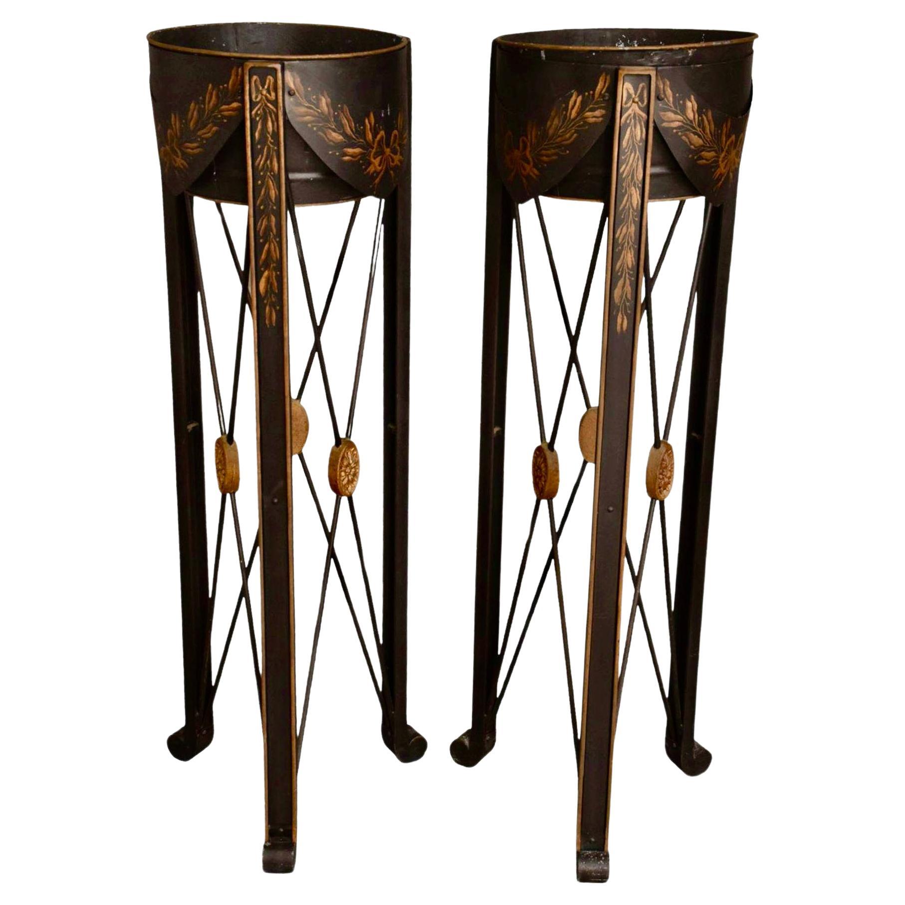 Pair of Nierman Weeks French Empire style tole planters. Planters feature tall X-based black plant stands with gold floral stenciling and gold medallions. Planters are removable from stand.
The tole plant stand design is based on a wooden planter