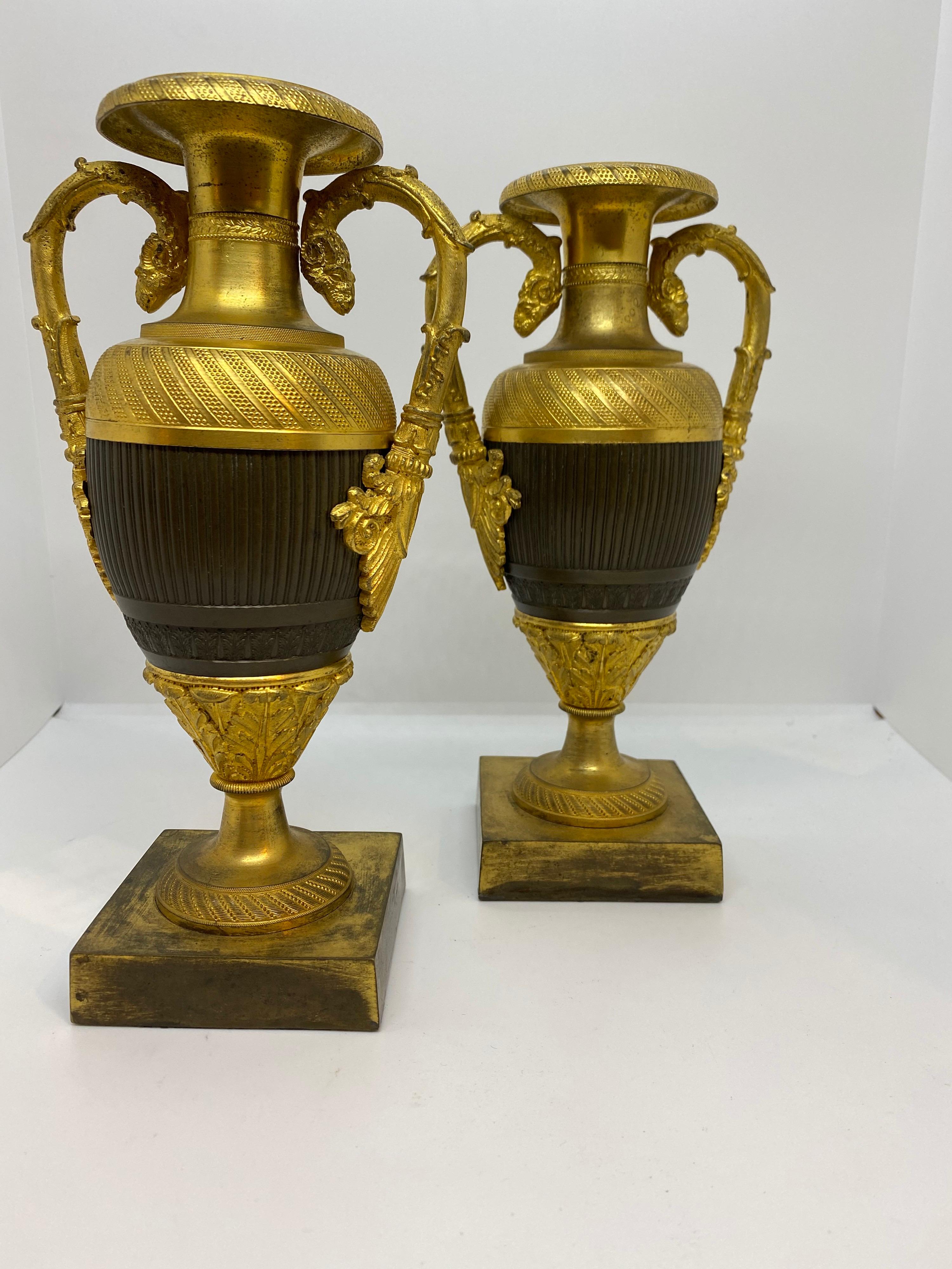 Pair of patinated and gilt bronze engine turned handled urns.