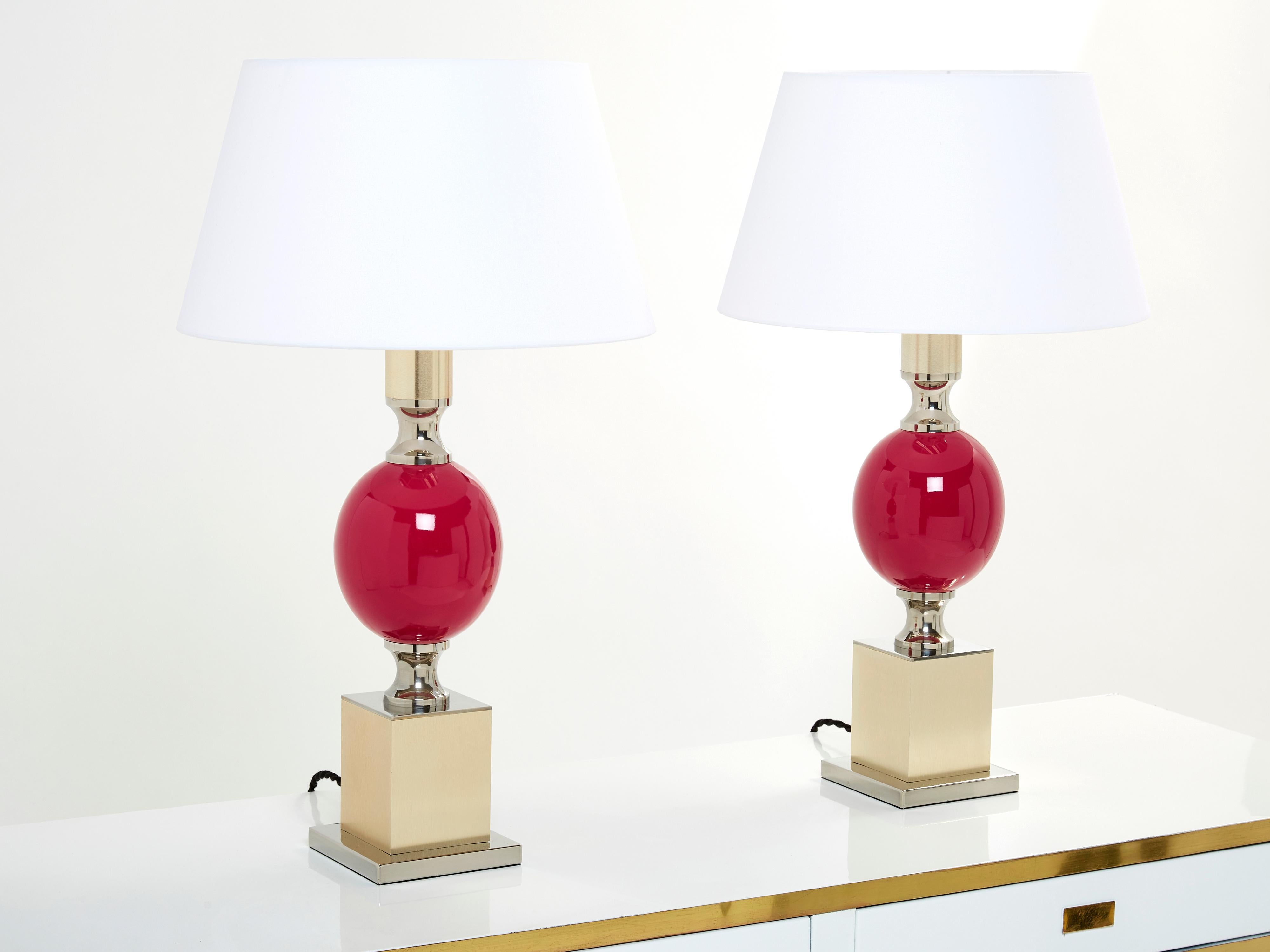 This Mid-Century Modern pair of lamps was designed by French lighting artist Philippe Barbier in the 1970s, and, with its bulbous fuchsia color enameled ceramic midsection topping a thick square base in a mix of chrome and brushed brass, is typical