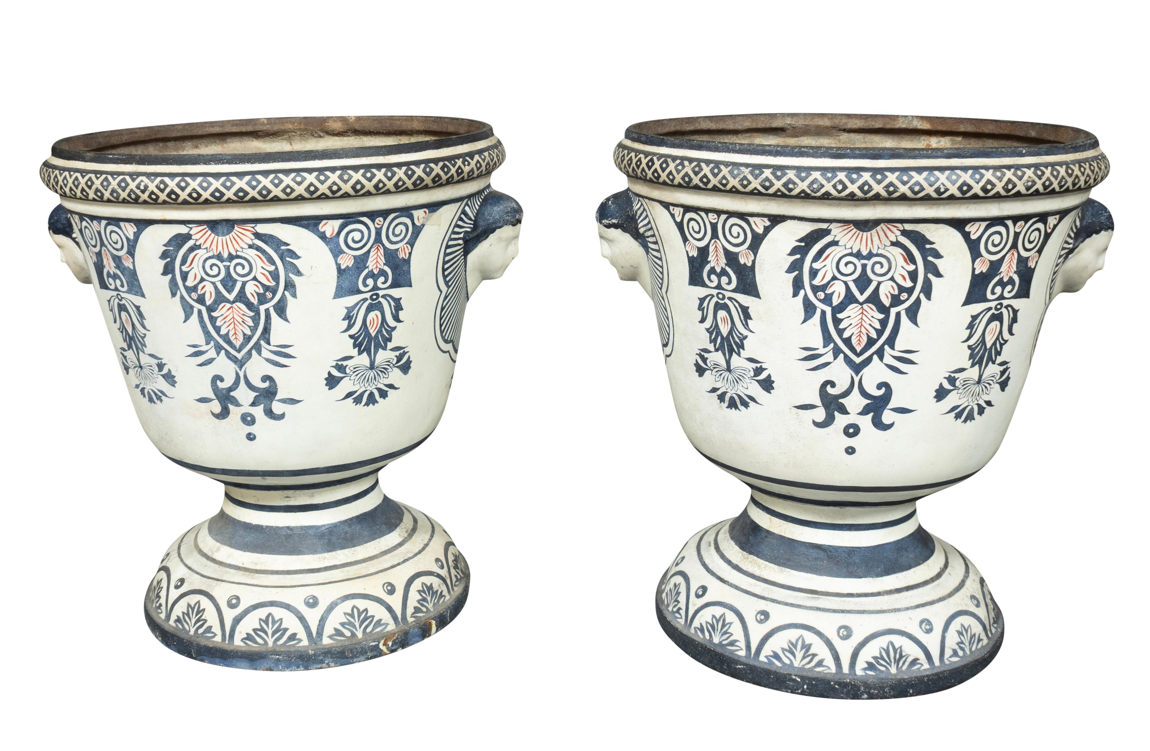 Each decorated in the style of French faience. The surface is an enamel impervious to rust. Heavy cast iron decorated with heads as handles.