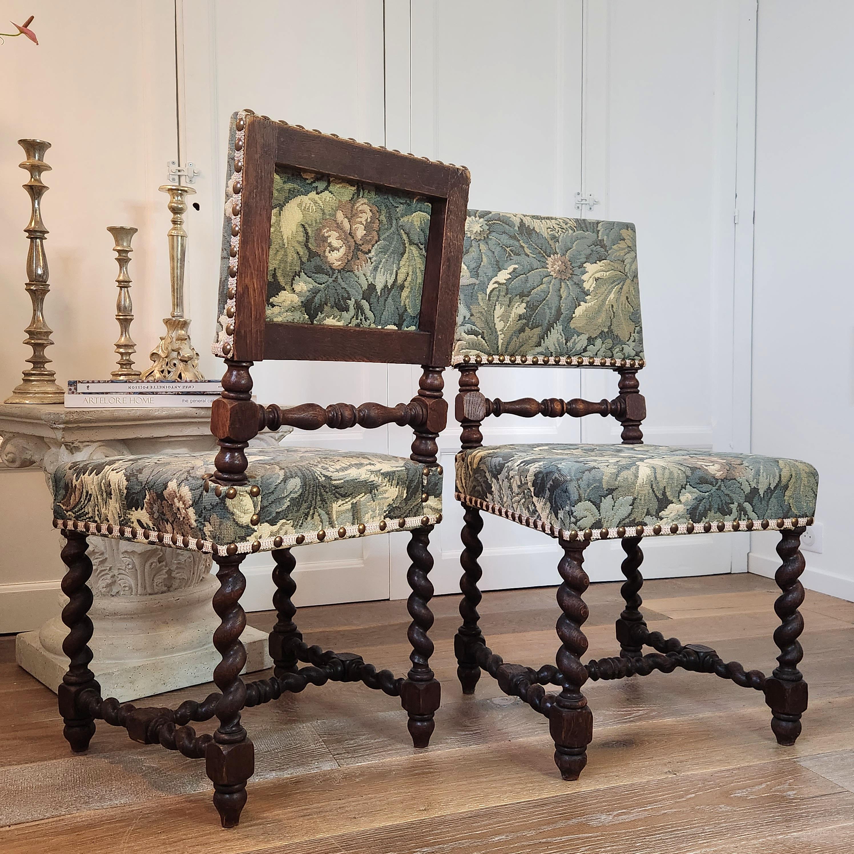 Elégante paire de chaises françaises du XVIIIe siècle qui se distinguent par leur magnifique cadre sculpté en noyer torsadé et leur impeccable tapisserie à décor floral encadrée de clous sur galon. 
